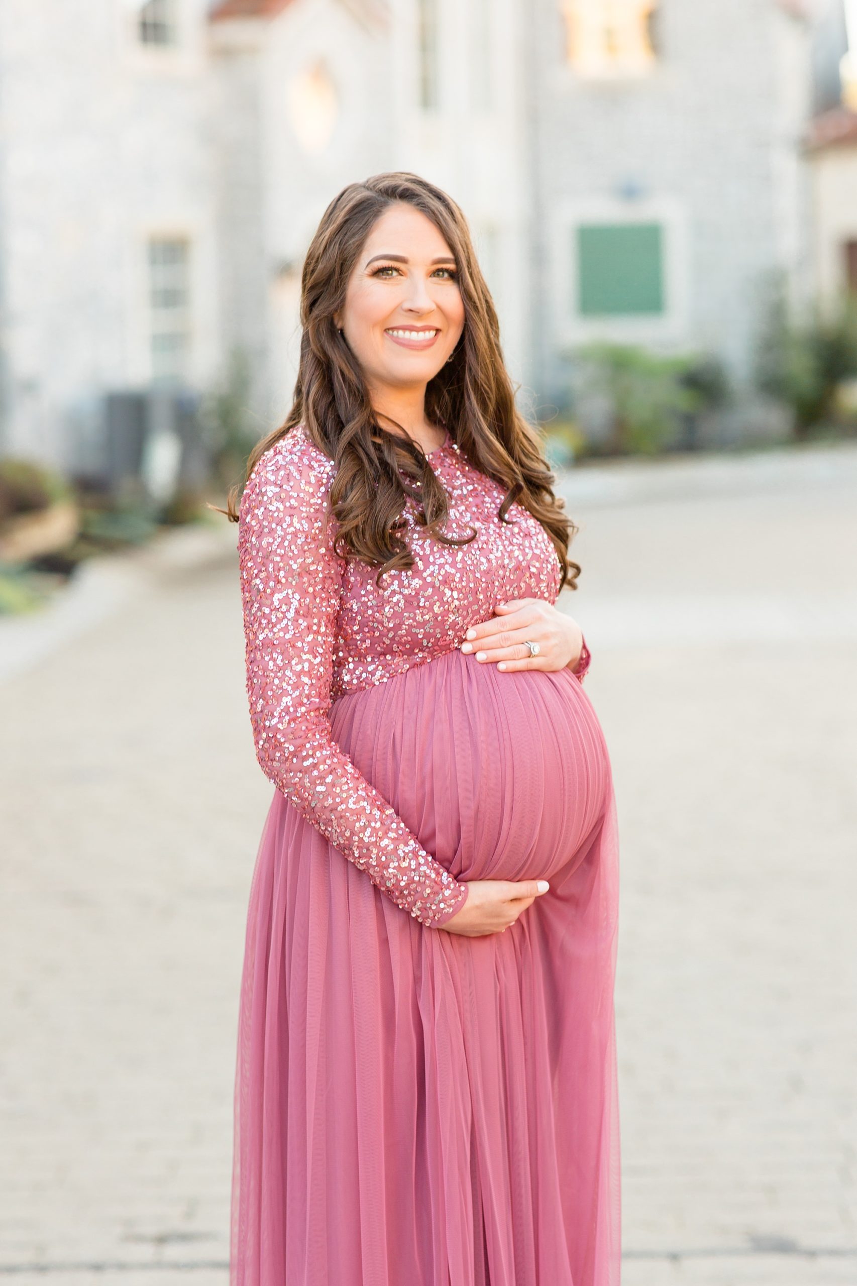 mom in pink maternity gown holds belly during McKinney Maternity Session