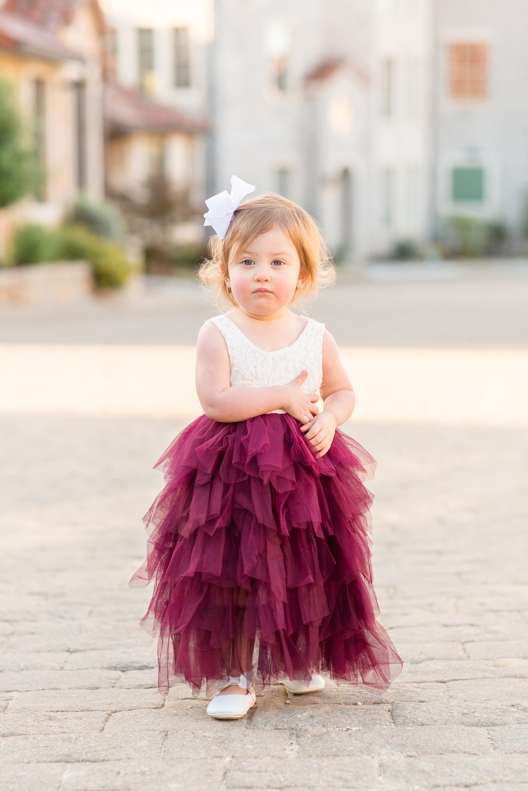 toddler poses in McKinney TX in red and ivory gown