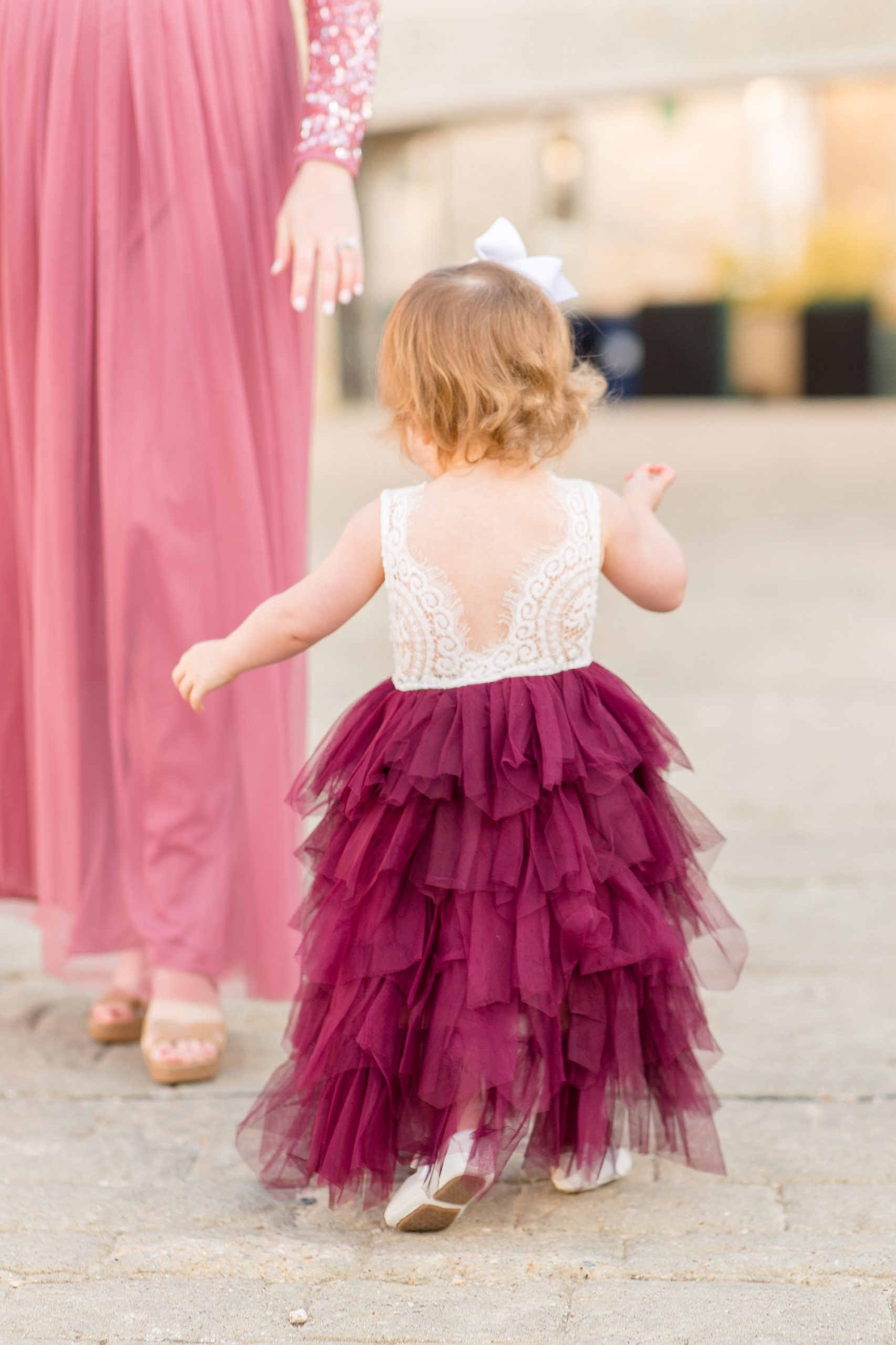 toddler in couture gown with red bottom walks during family photos