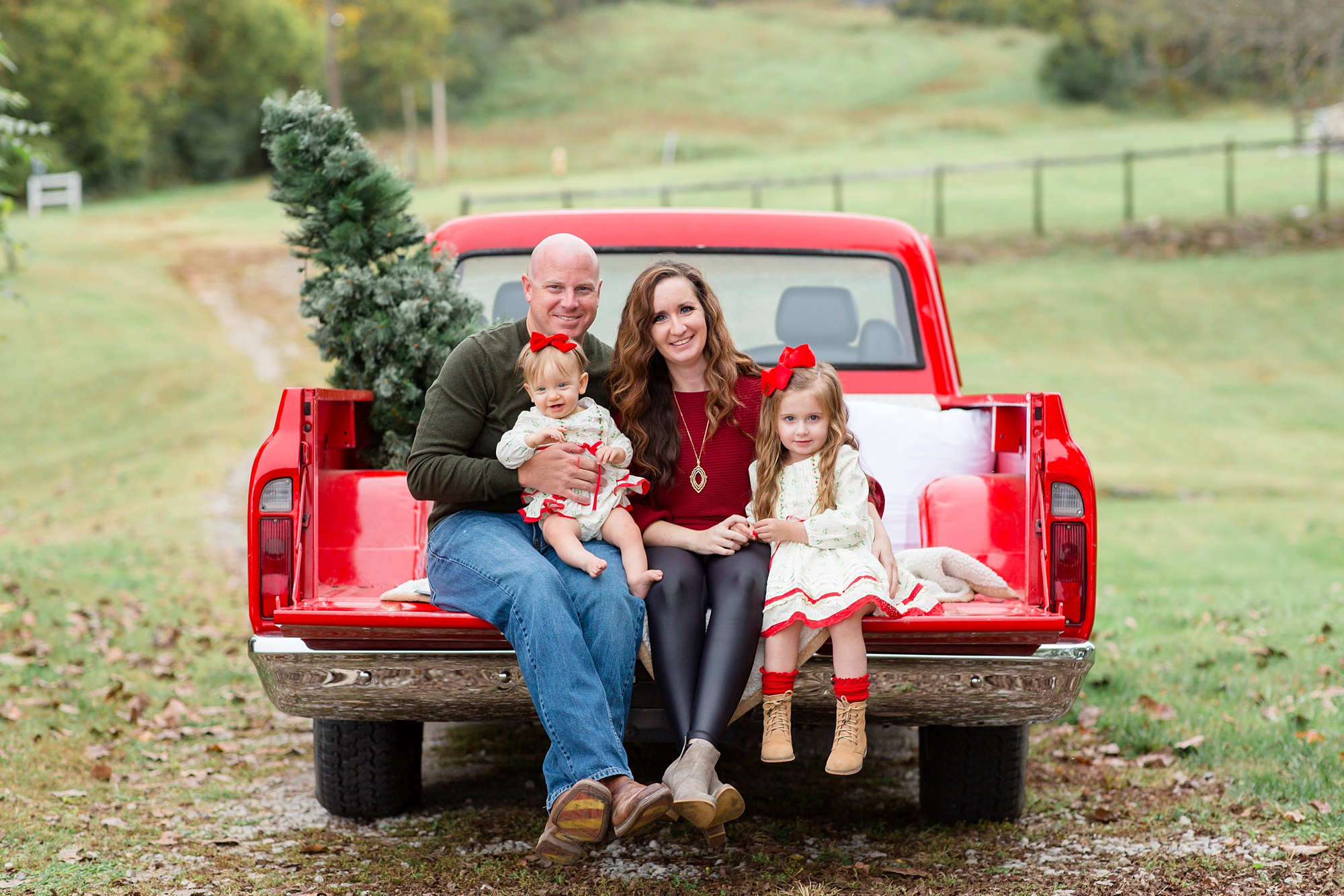 parents post with daughters during Franklin Tennessee Red Truck Christmas Minis