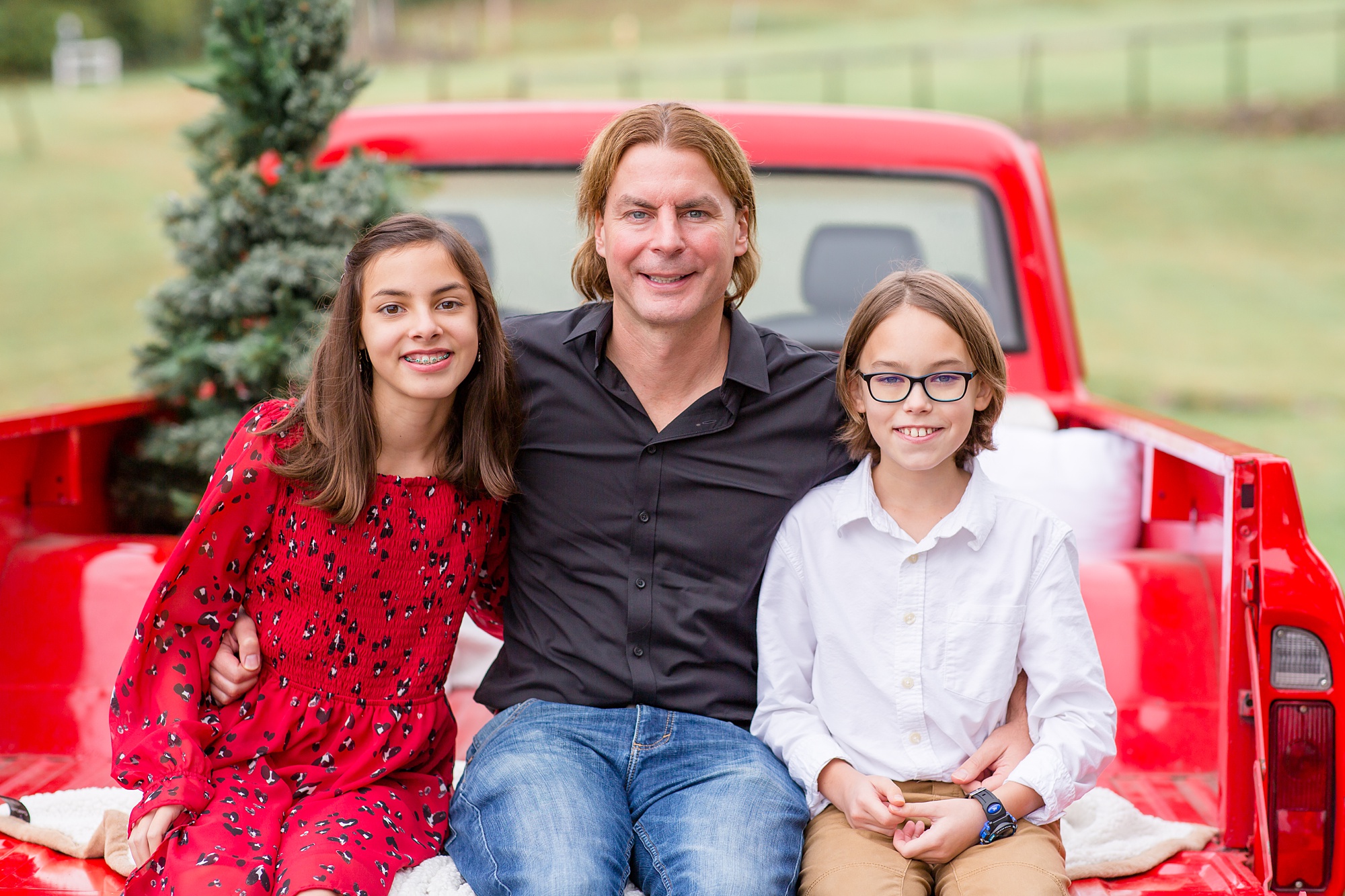 dad holds kids in back of red truck during Tennessee Red Truck Christmas Minis