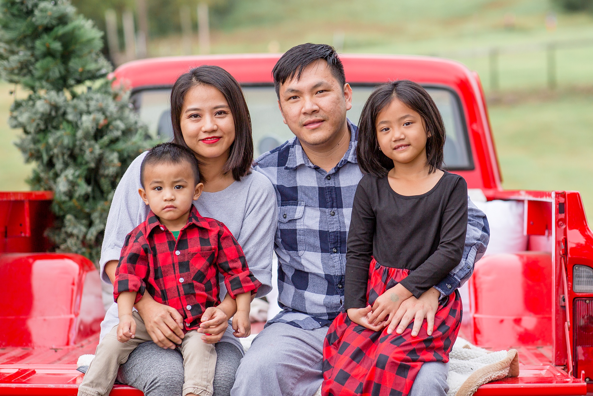 family of four sits in back of red truck