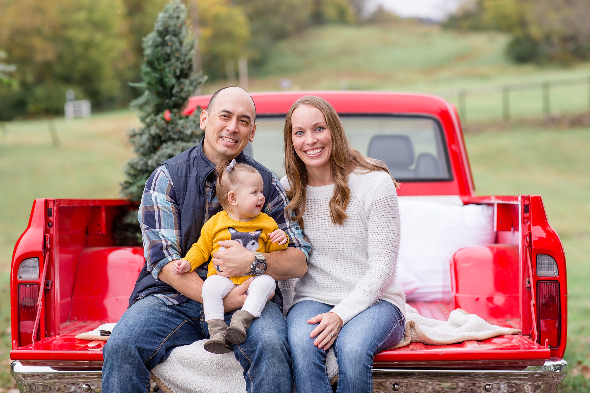parents pose with toddler during Tennessee Red Truck Christmas Minis in Franklin TN