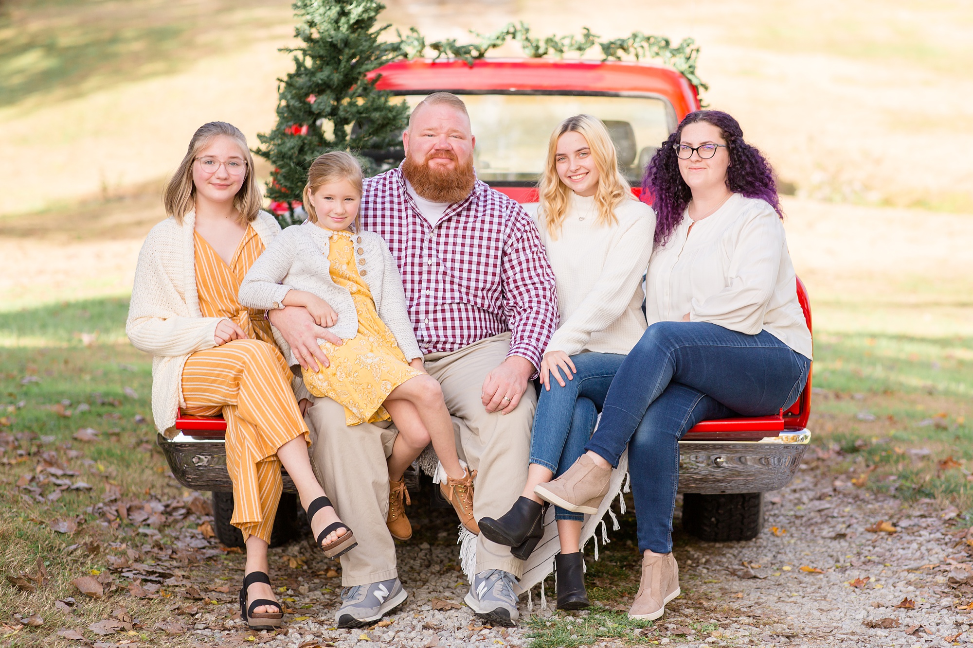 dad sits with four daughters during Tennessee Red Truck Christmas Minis
