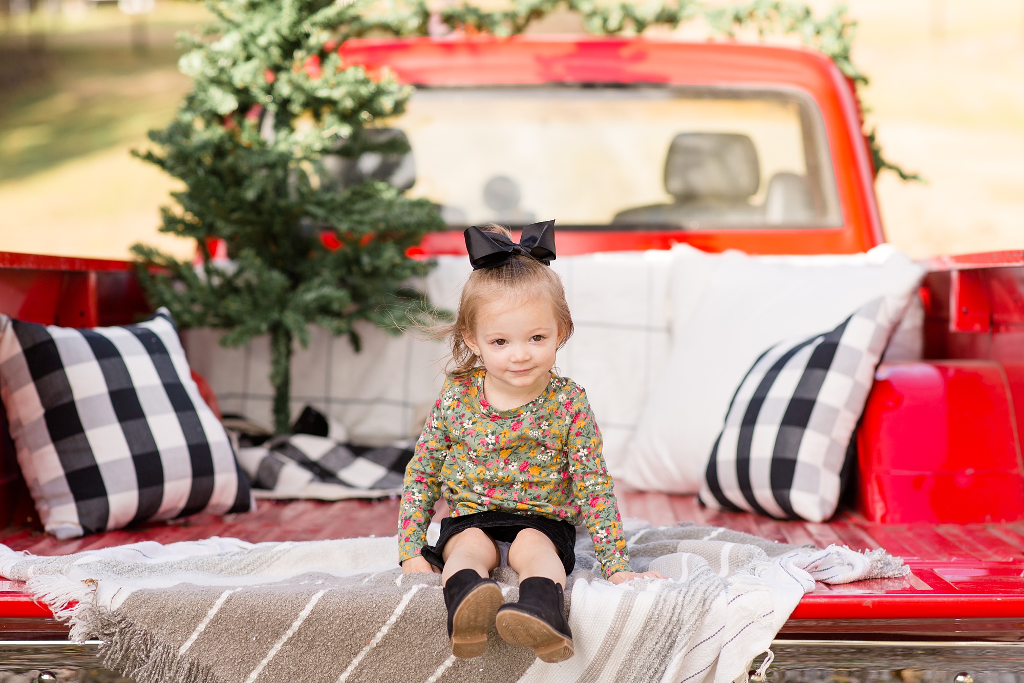 little girl sits on decorated truck bed during holiday mini sessions in Franklin TN