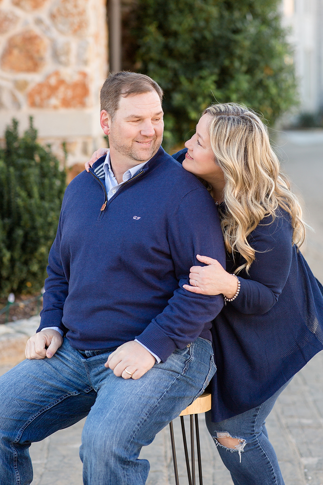 husband and wife pose on stool during family photos in Texas