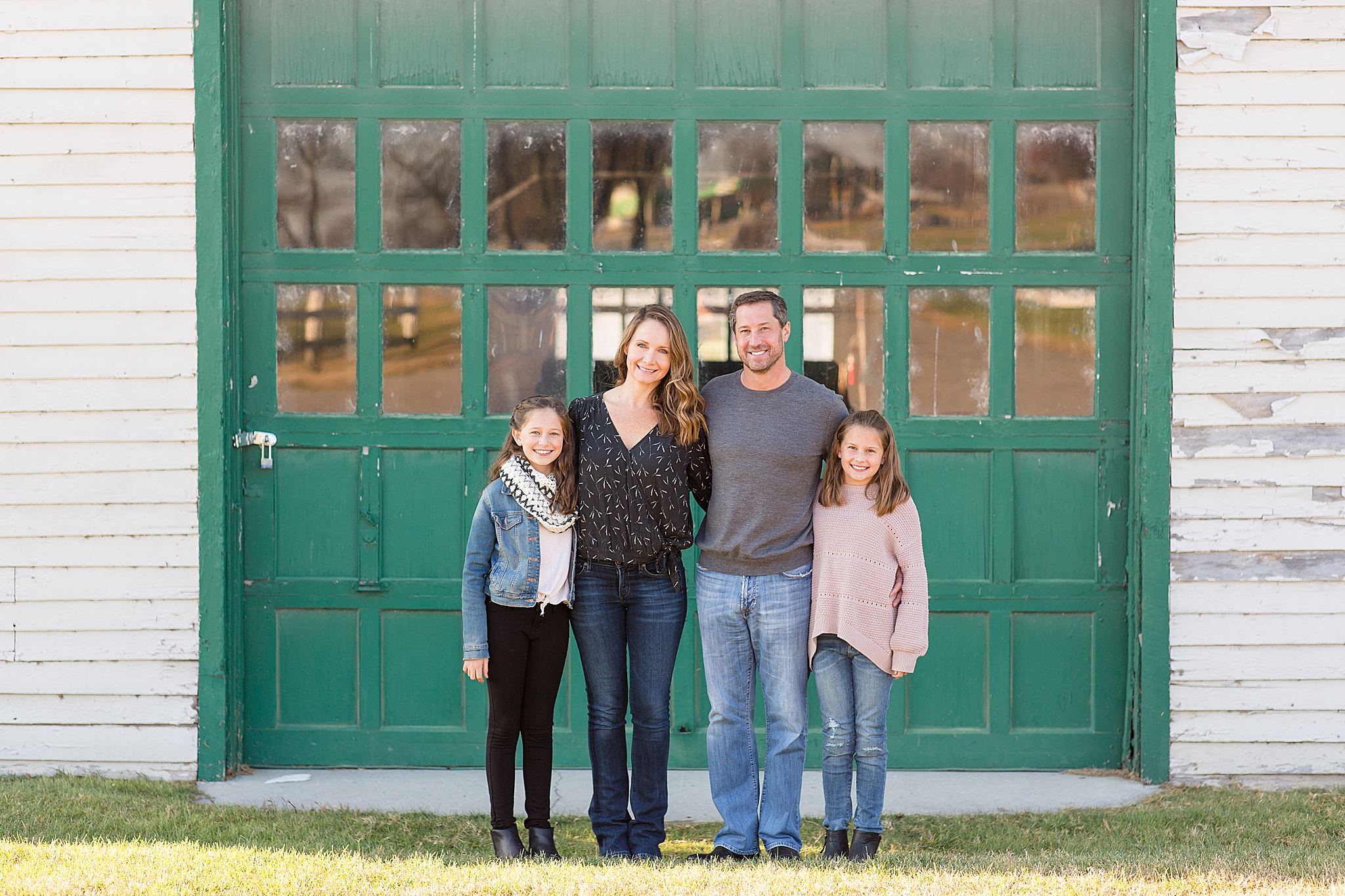 family of four poses in front of tael barn at Harlinsdale Farm