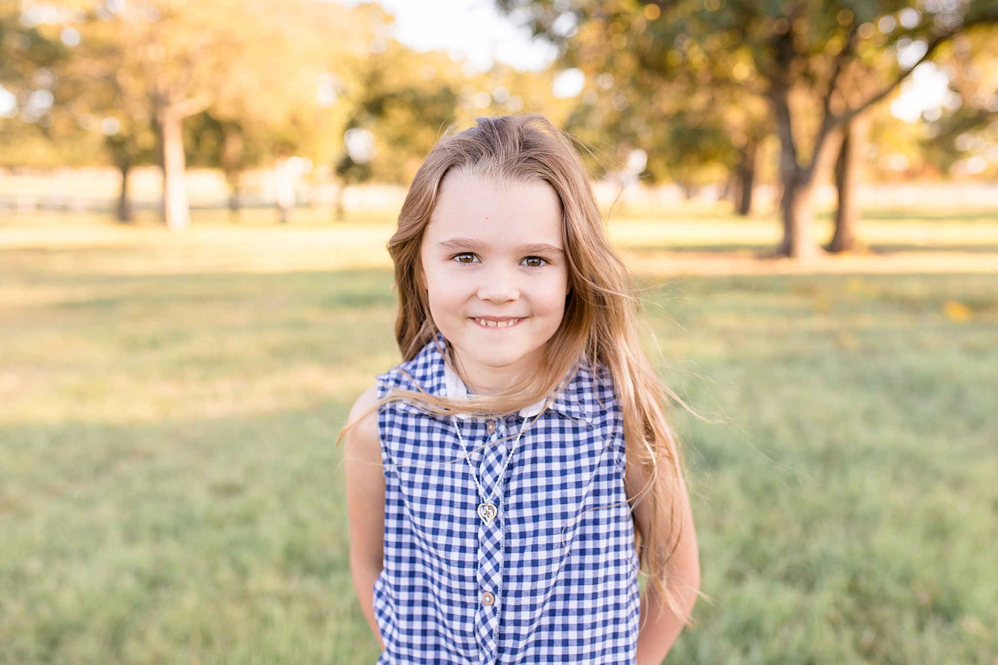 little girl poses in gingham shirt on McKinney family farm