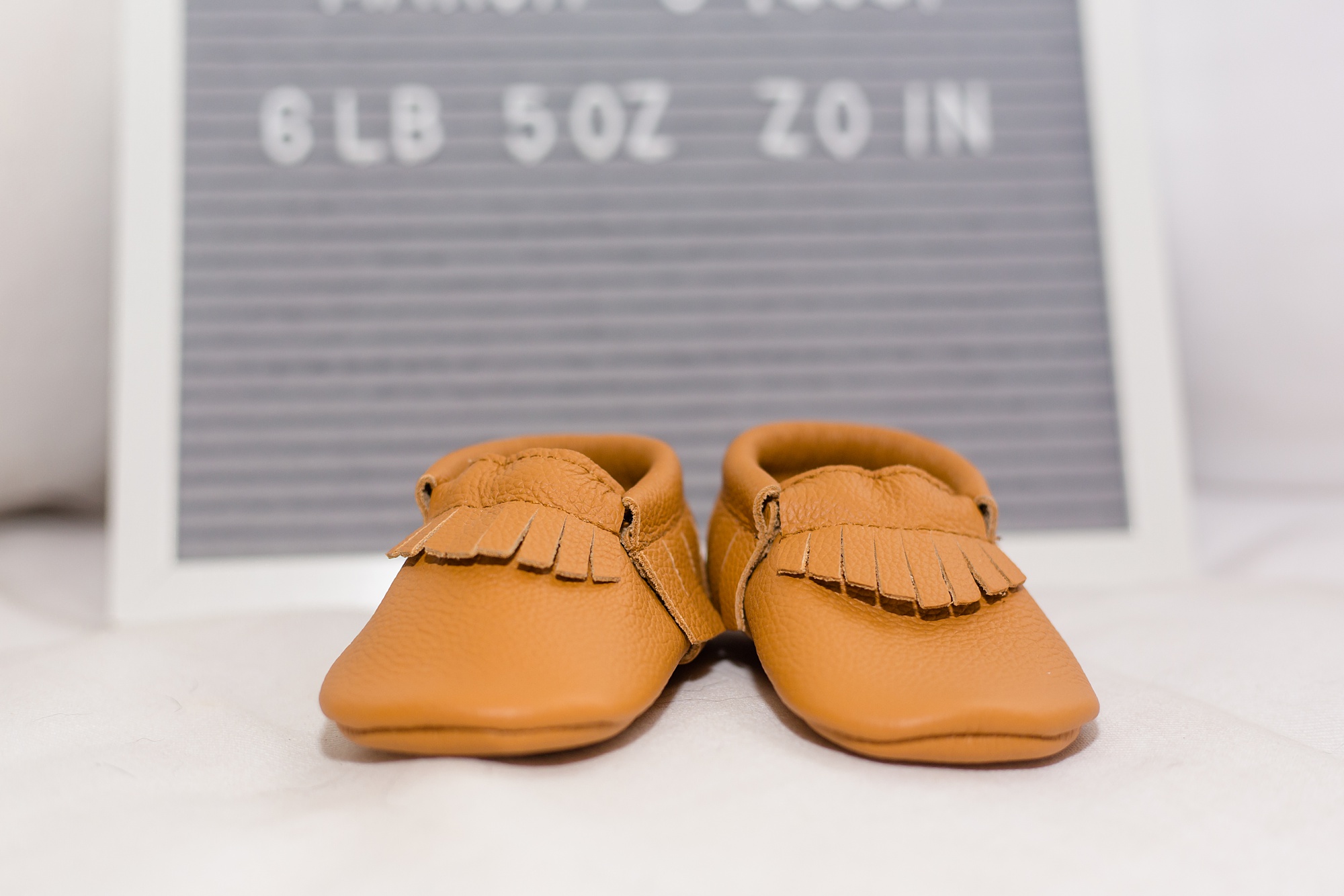 baby moccasins near announcement board for new baby