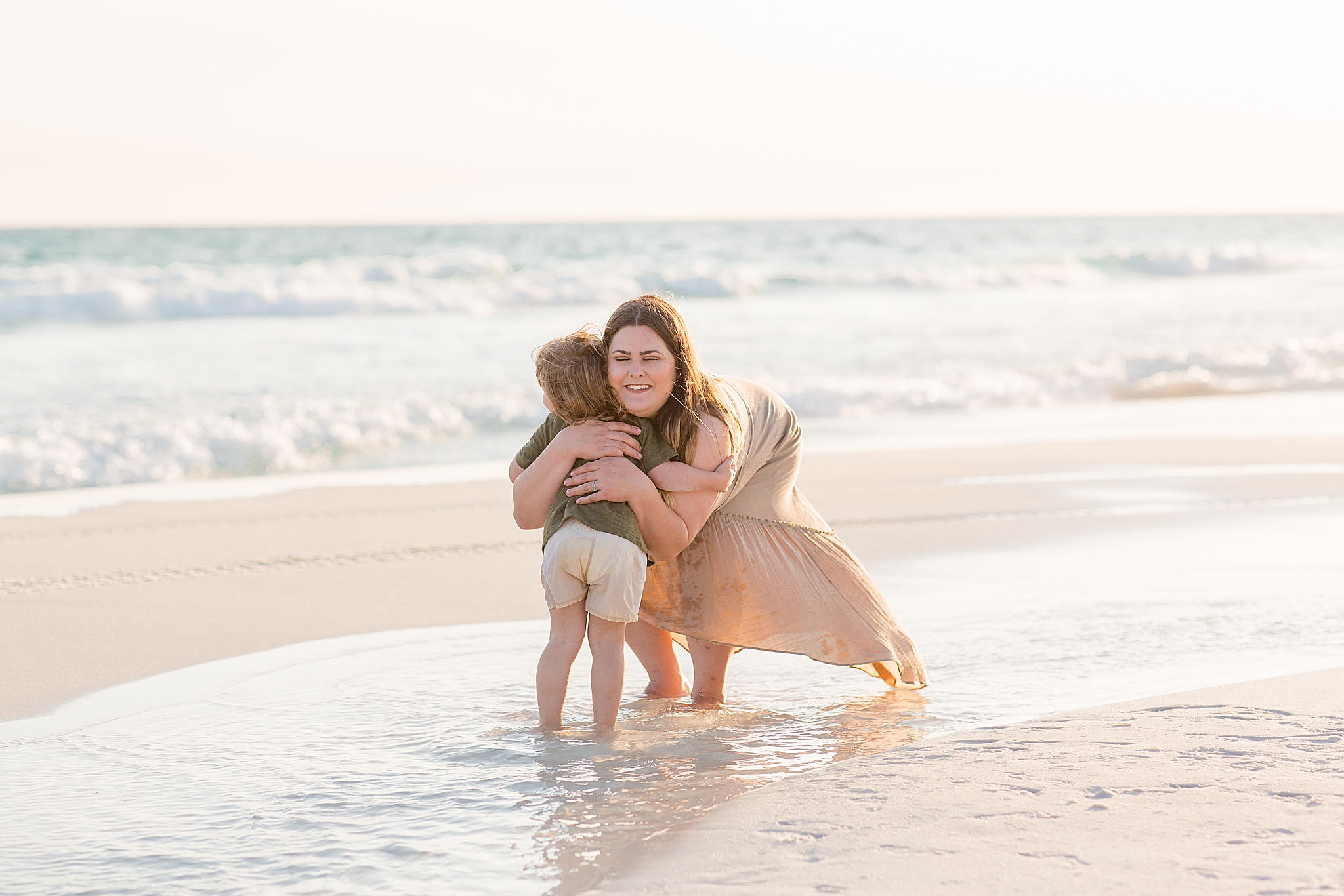 mom and toddler hug on the beach