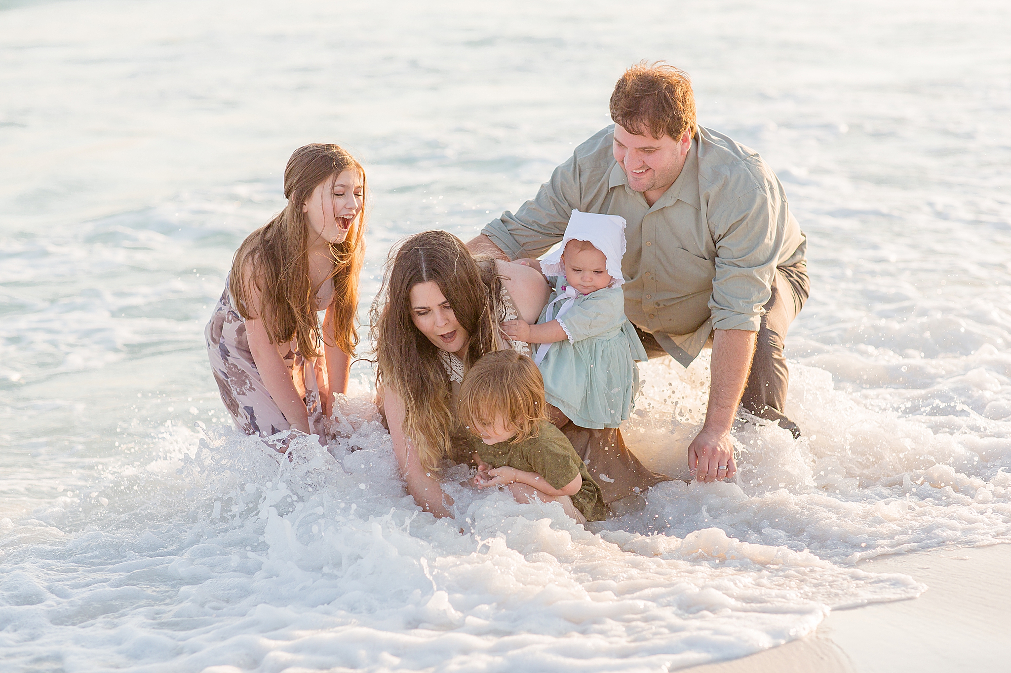 family falls over into water during beach photos