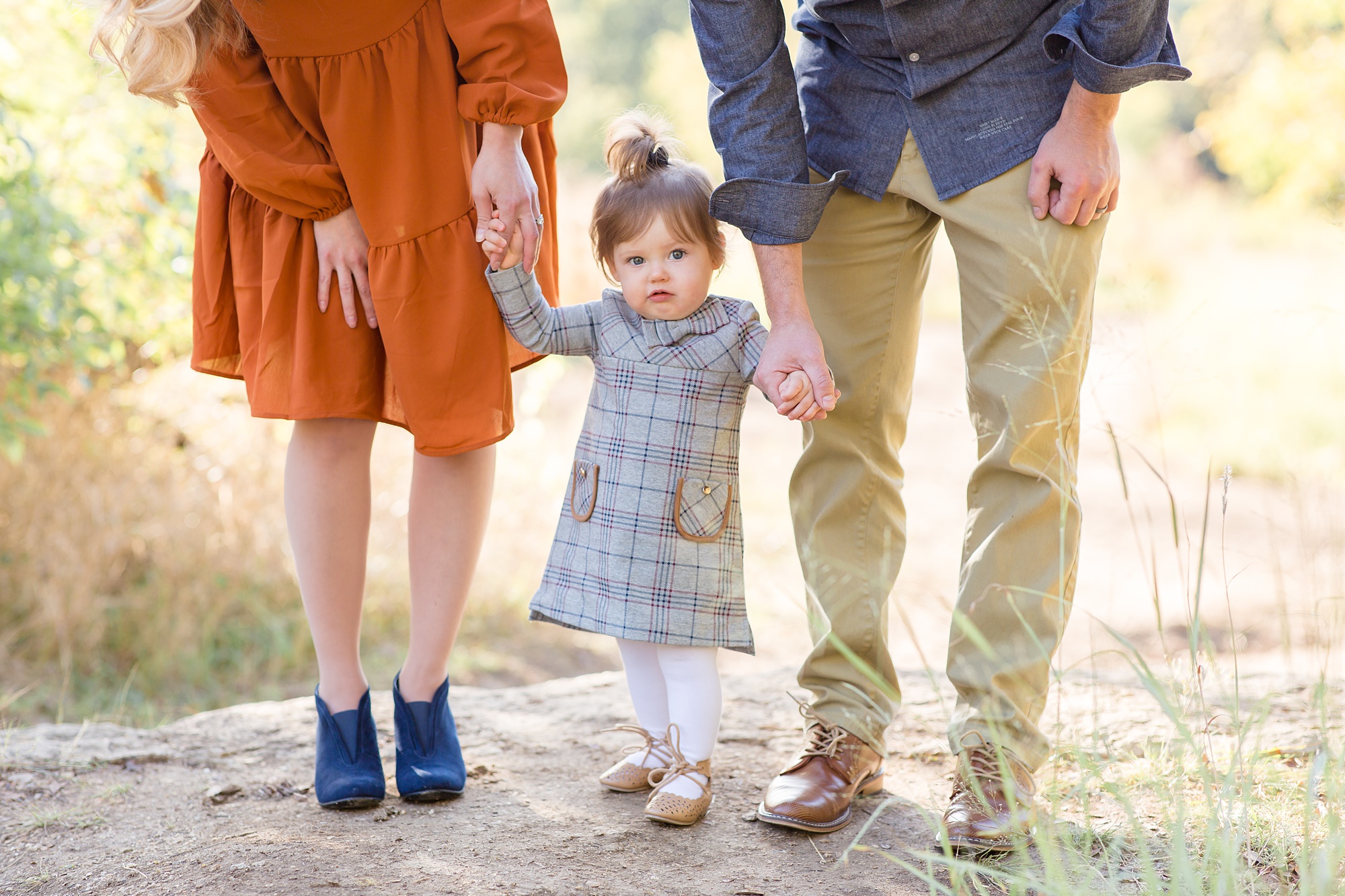 couple holds daughter's hands walking through family portraits