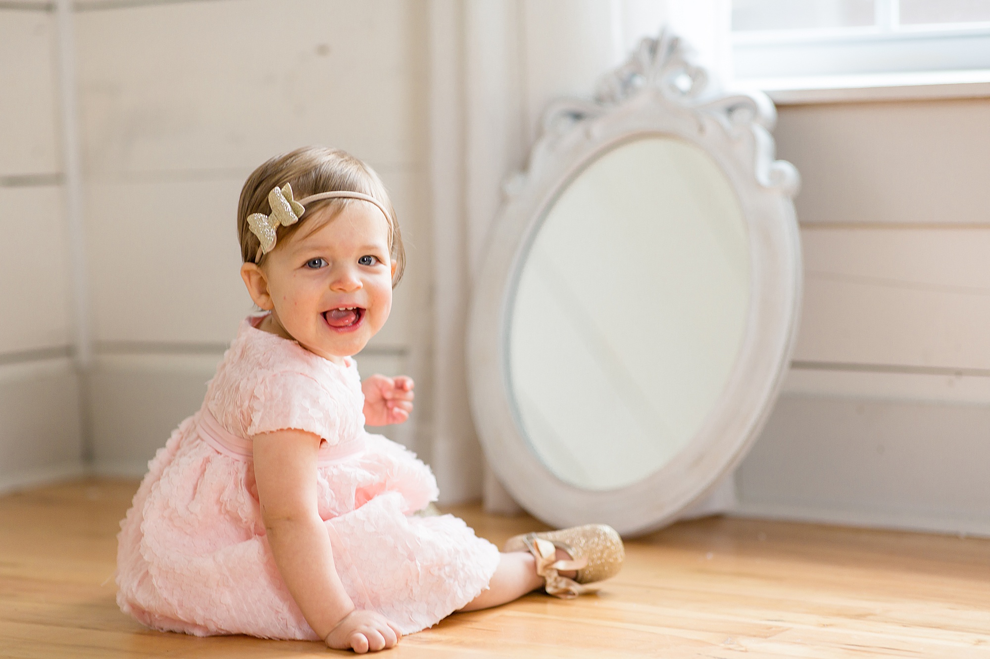 baby laughs sitting by mirror for milestone photos in Texas