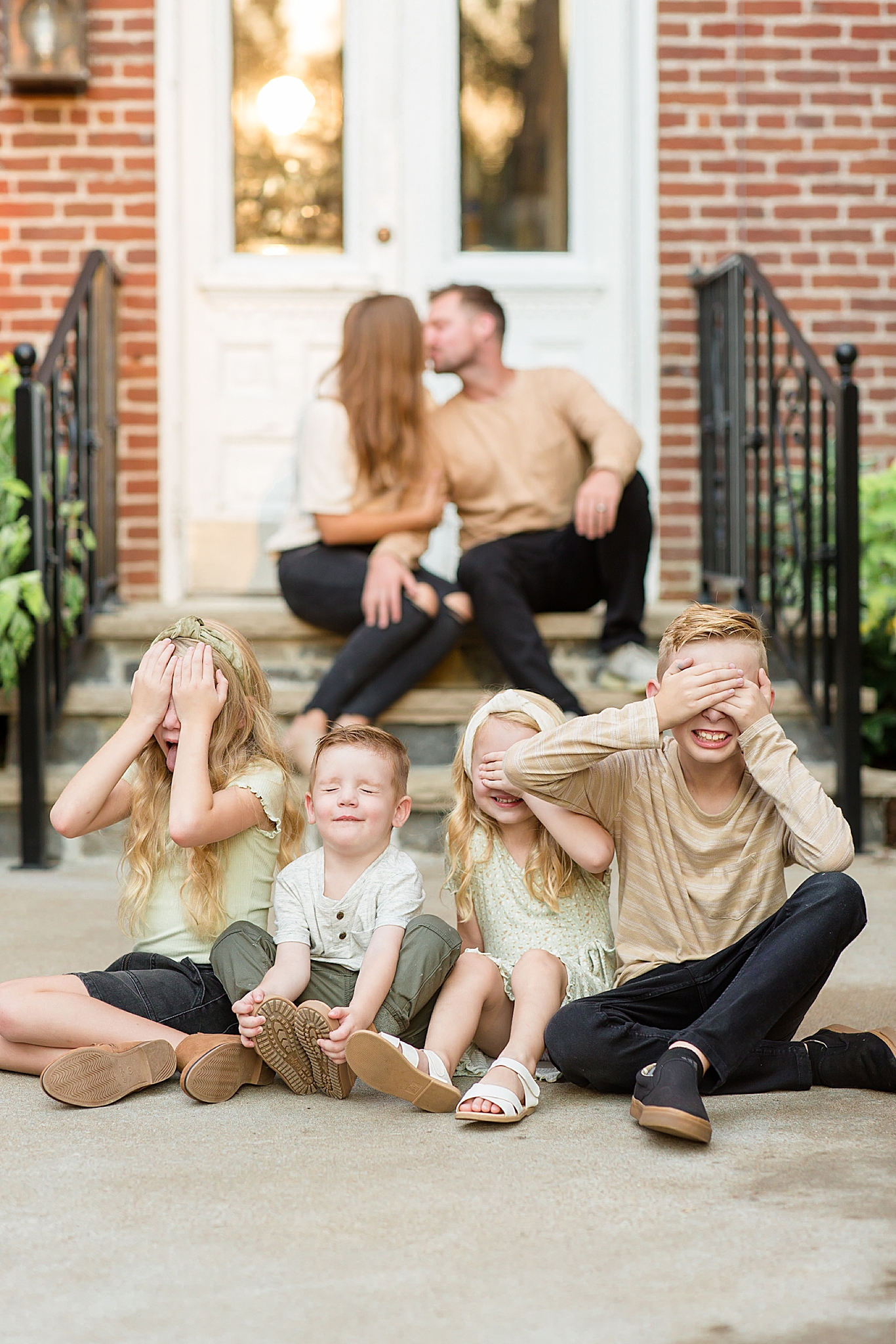 kids make funny faces while parents kiss during Spring Hill family portraits
