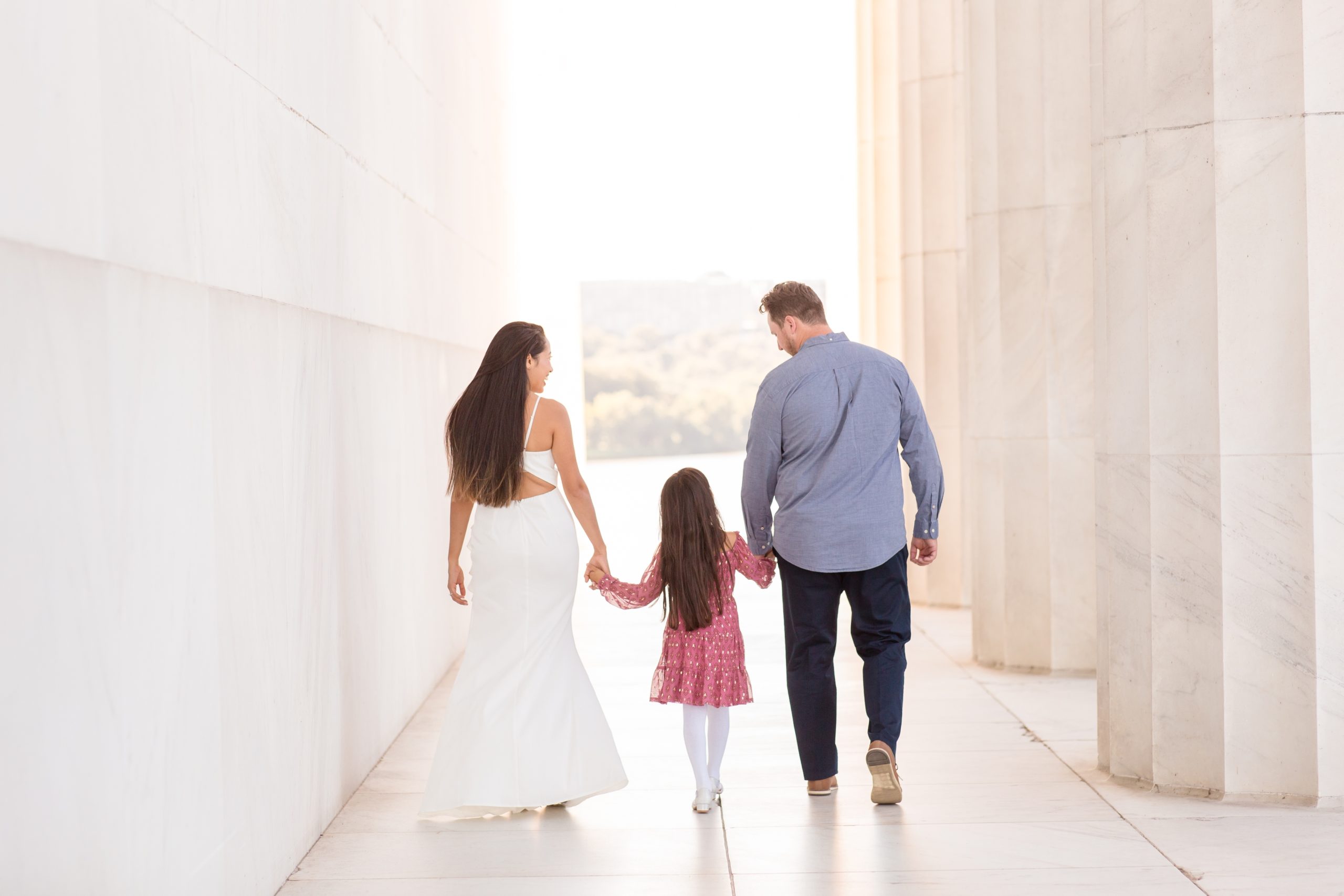 Family of 3 walks while holding hands at the Lincoln Memorial during family portrait session with Rebecca Rice Photography