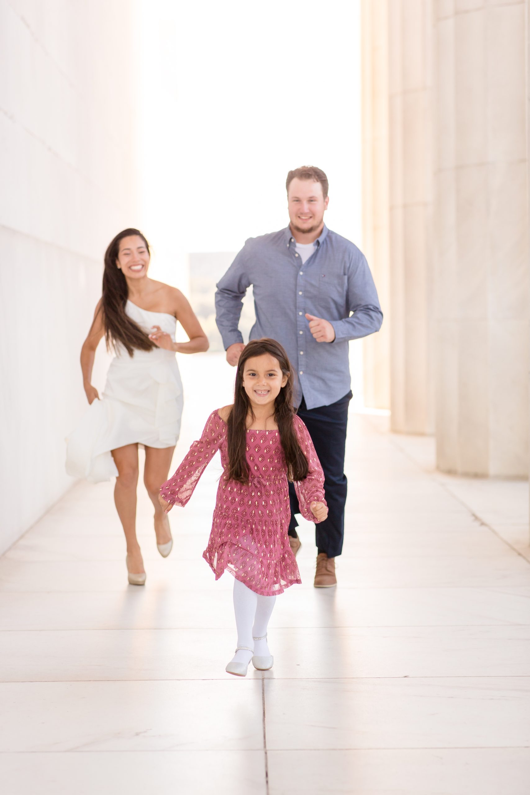 Parents chase daughter in pink dress during family portrait session at memorial in washington, dc with Rebecca Rice Photography 