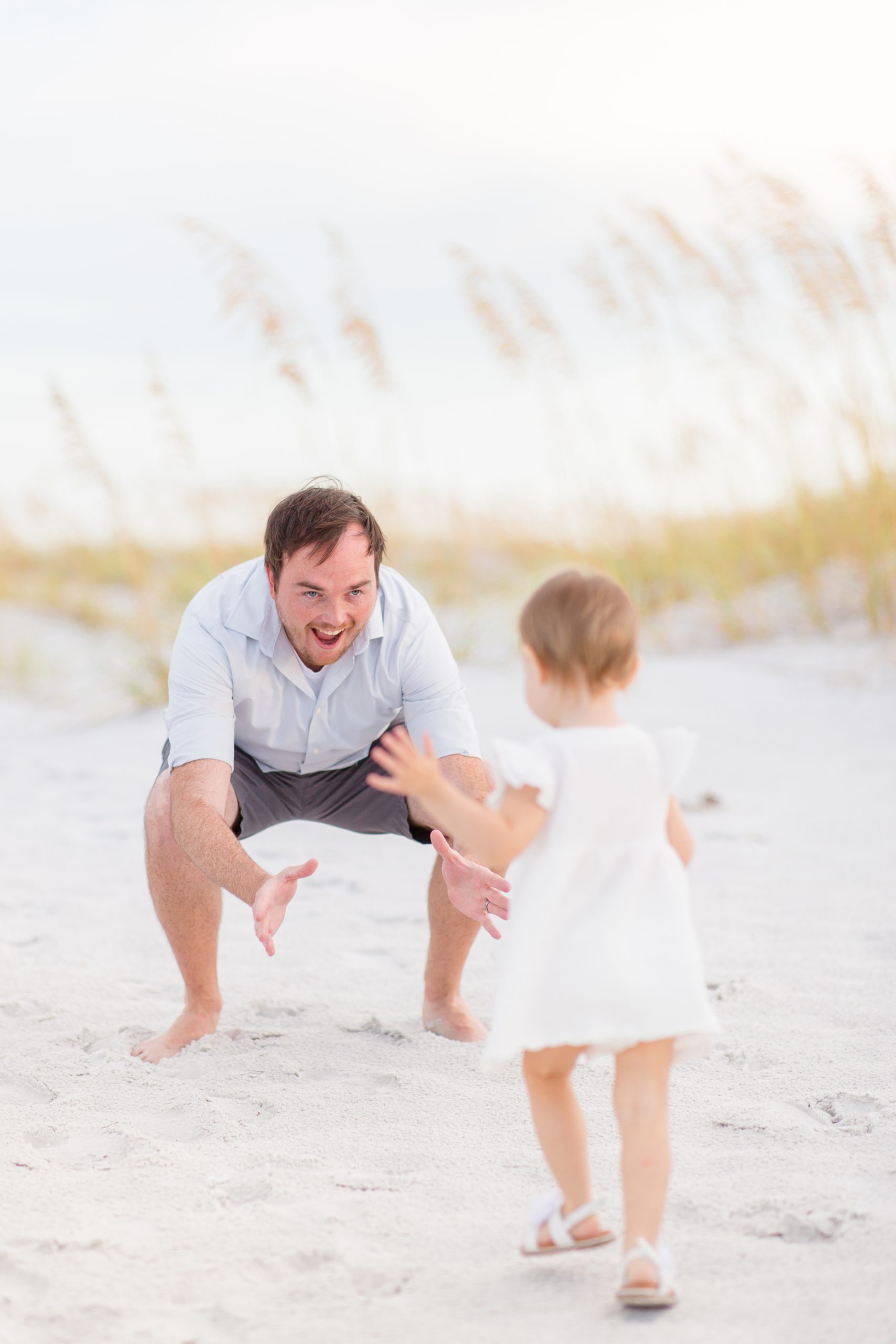 Daughter runs to dad during family portrait session on the beach at Anna Maria Island, Florida. Click to see more fro this session by Rebecca Rice Photography! 