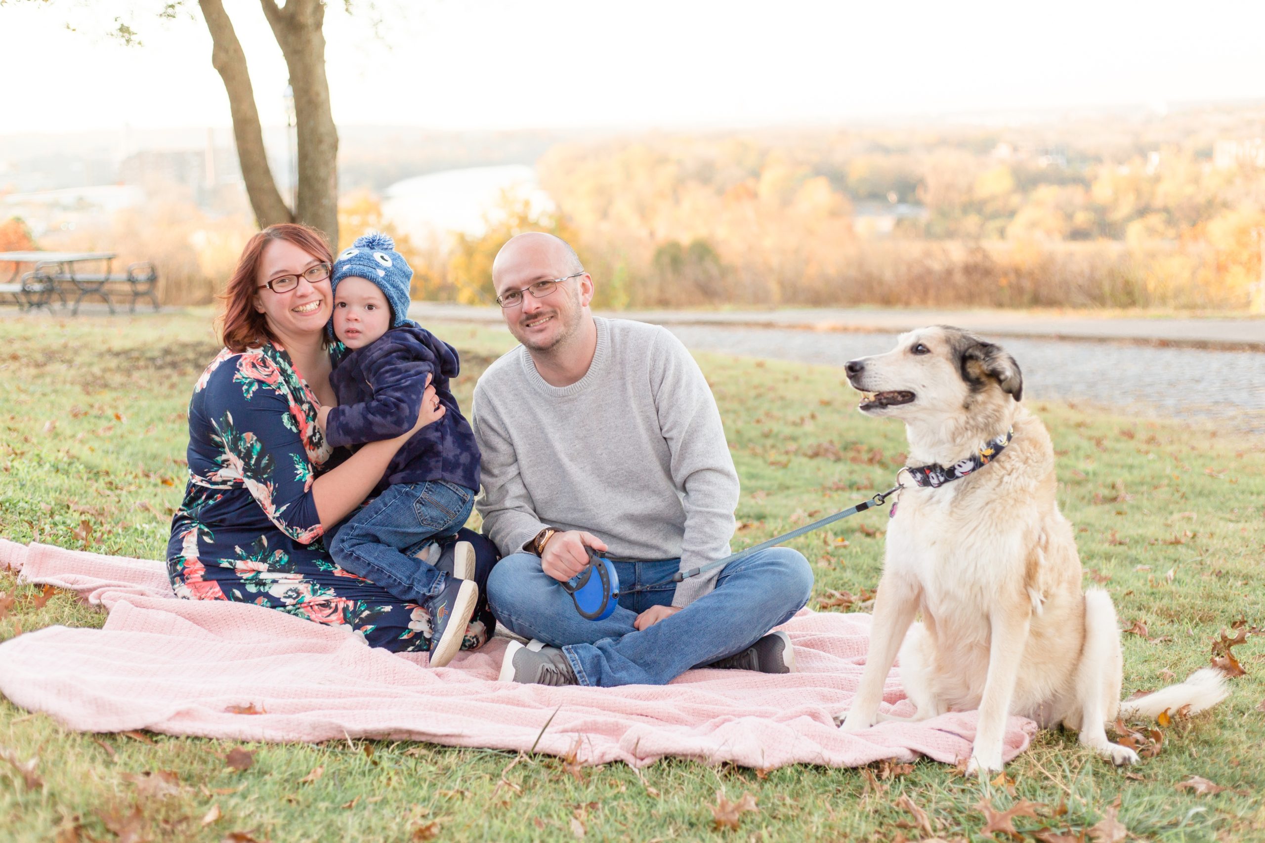 Family of 3 sits on pink blanket with their pup during family portrait session at Libby Hill Park in Richmond, VA with family photographer and educator Rebecca Rice of Rebecca Rice Photography. Click to see more from this session on the blog!