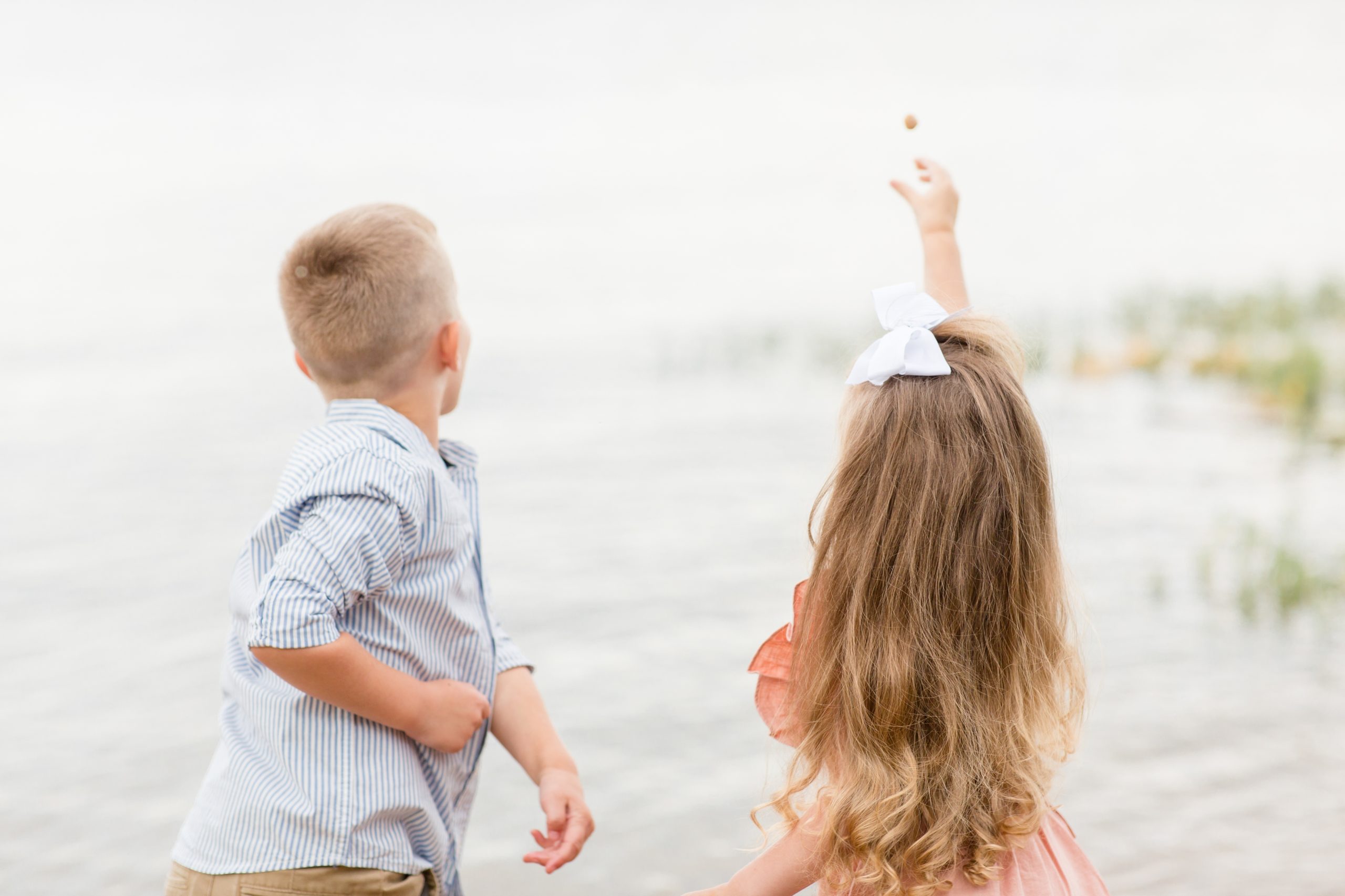 Siblings stand next to each other and throw rocks in James River during fall family portrait session with Rebecca Rice Photography. This session was featured on my monthly membership, Behind the Lens! Click to read more about it on the blog now! 