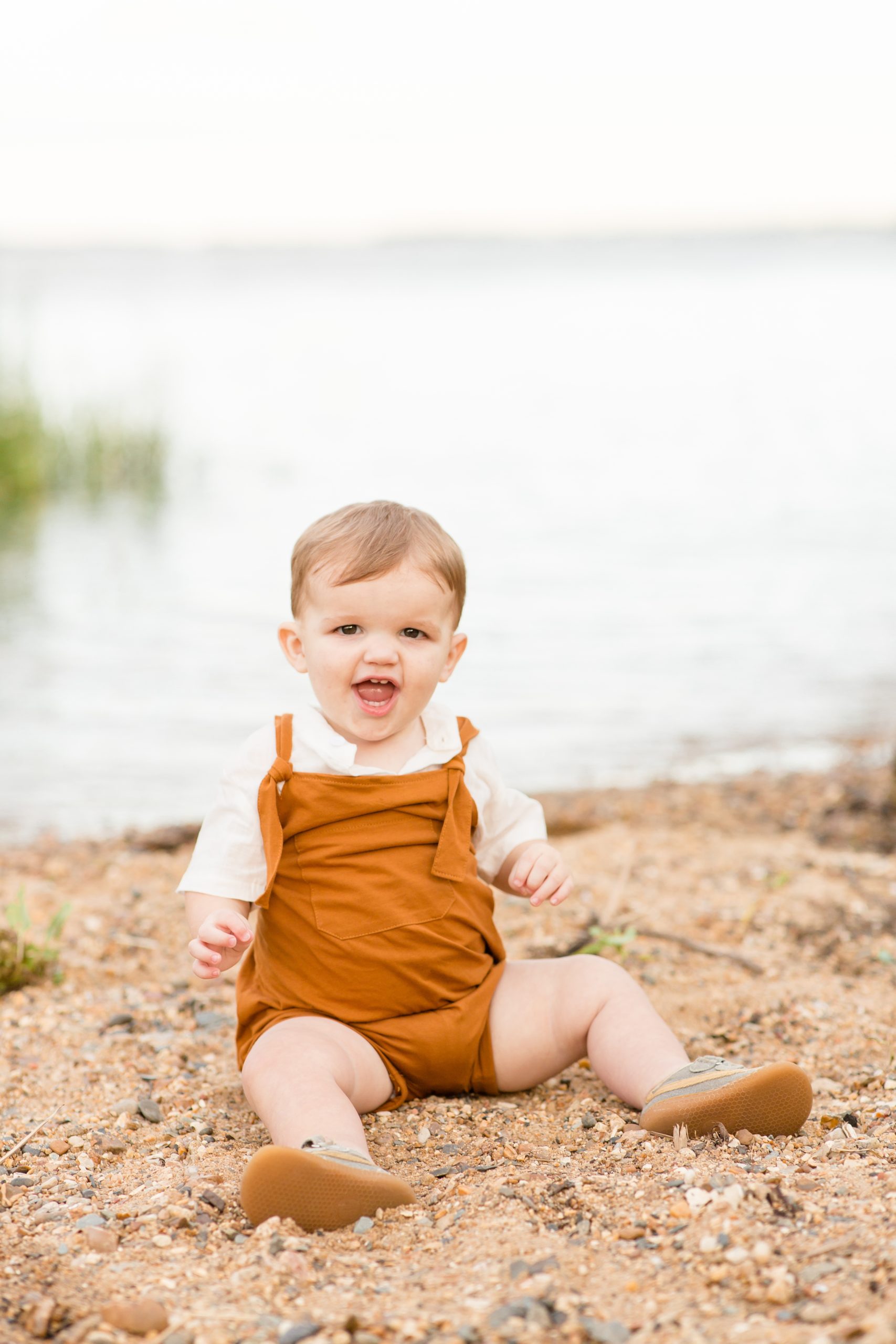 Boy in orange jumper sits next to James river during fall family portrait session with family photographer Rebecca Rice Photographer. Click to read more from this session on the blog! 