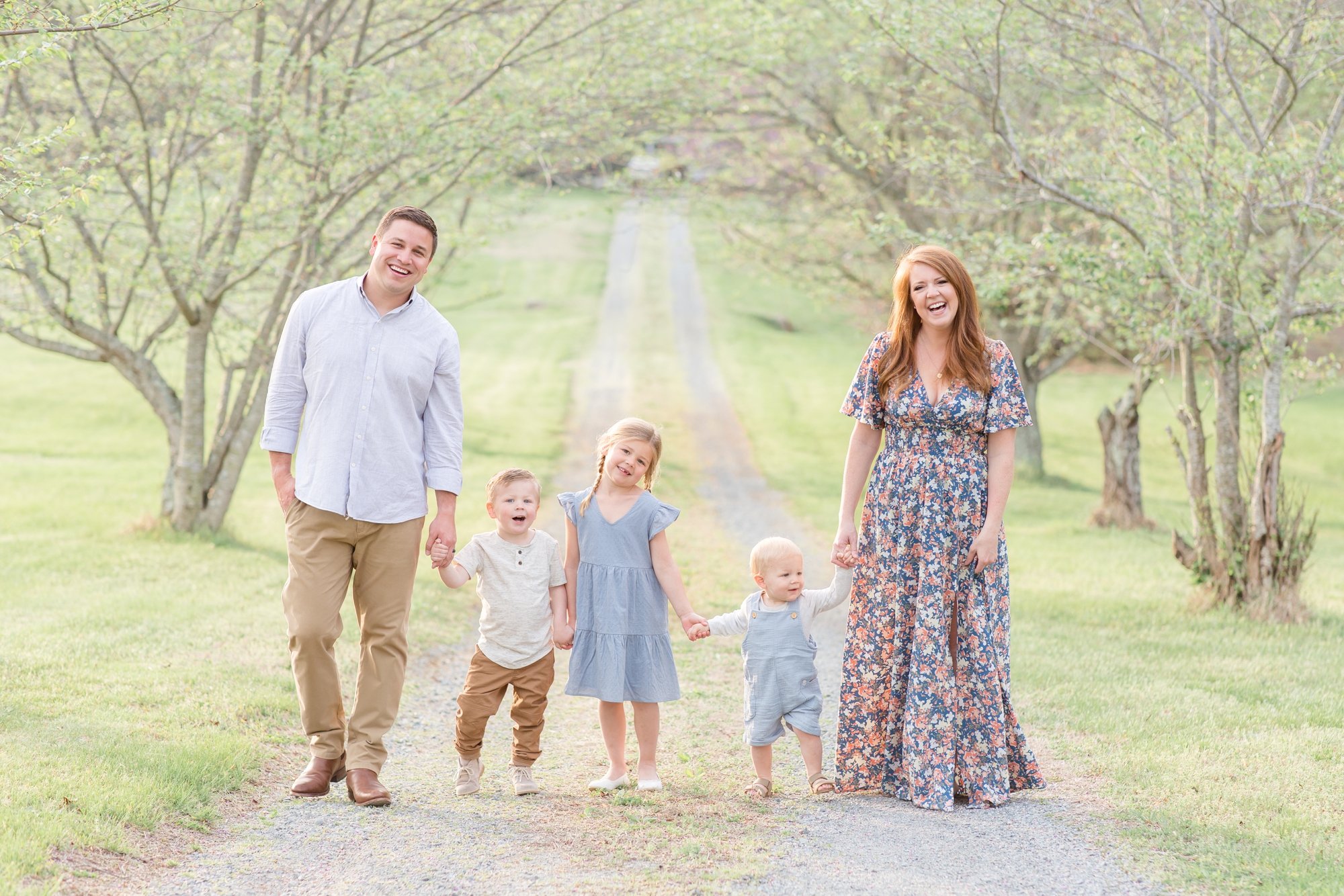 Family of 5 poses while holding hands on gravel path between trees during family portrait session in the spring in Richmond, Virginia with family photographer and educator Rebecca Rice of Rebecca Rice Photography. Click to seem more from this sweet session live on the blog now! 