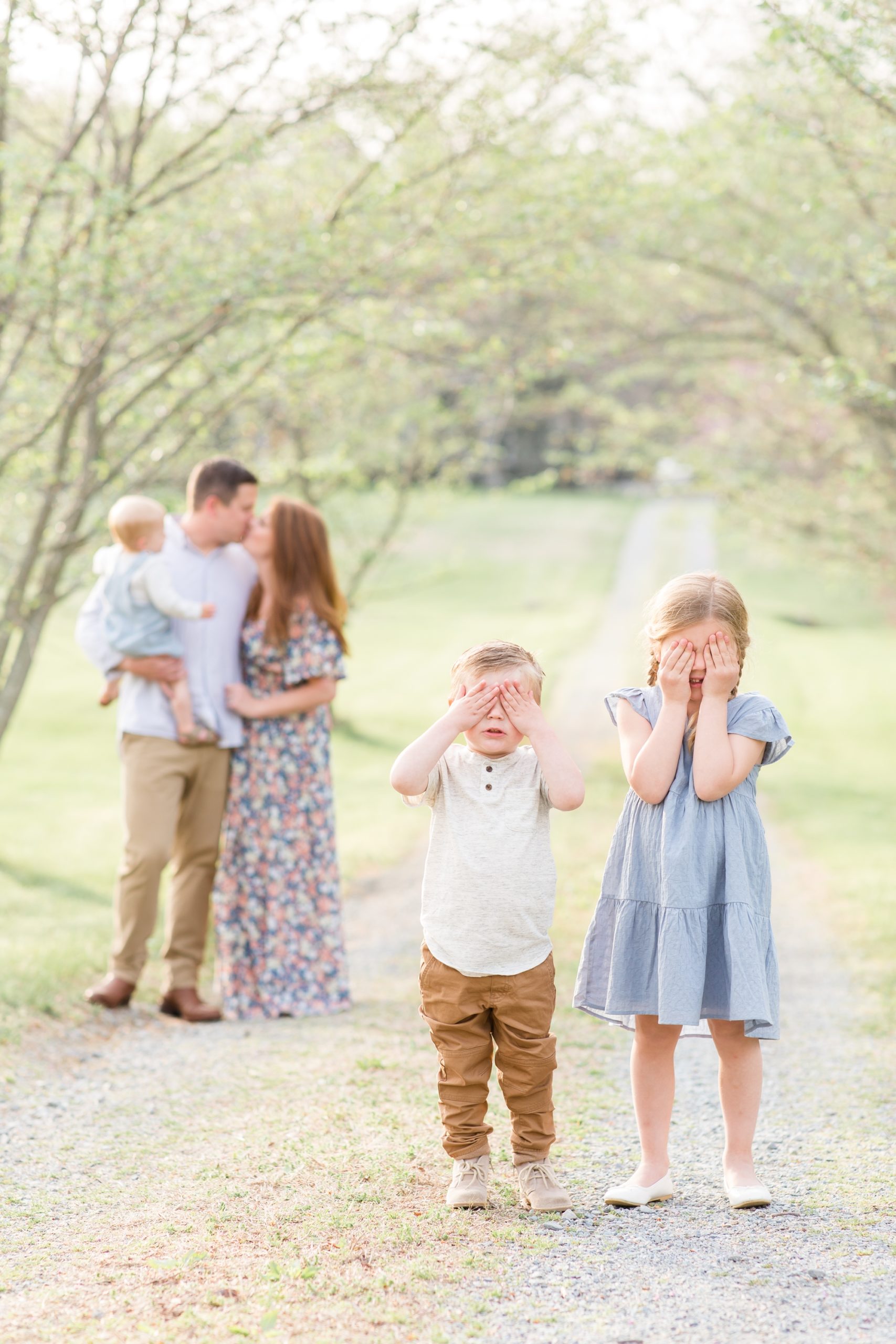 Kids cover their eyes while parents kiss in the background during family portrait session with Katelyn James and her precious family! This family of 5 was so much fun and I'm honored I was able to capture them. Click to see more from this session live on the blog now! 