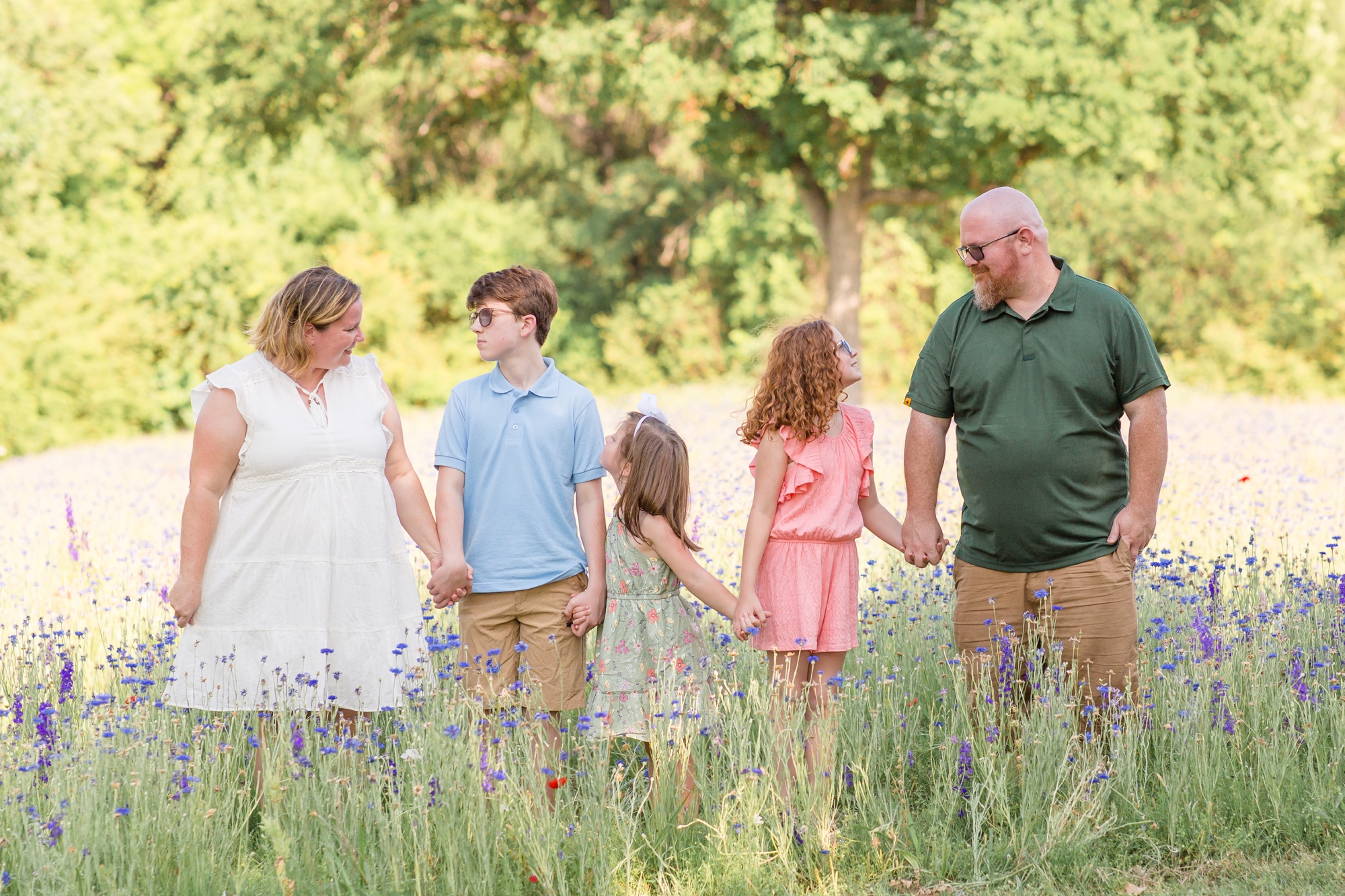 Family of 5 poses hand in hand in wildflower field during family mini session in Richardson, TX with family photographer and educator Rebecca Rice of Rebecca Rice Photography. 