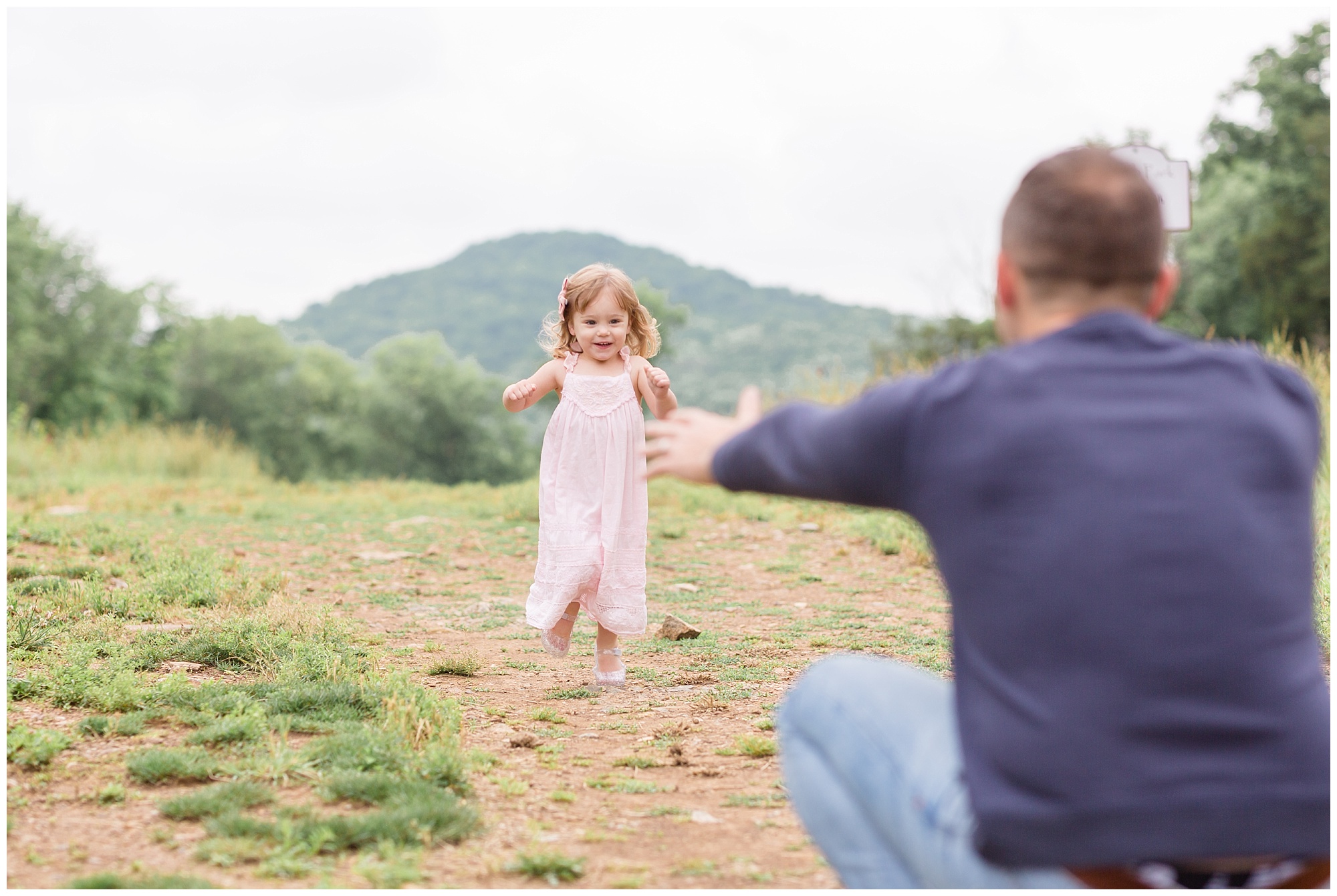 This sweet little girl is running to her daddy in this beautiful open area in Nashville, TN. Dad is wearing a long sleeve navy blue shirt and blue jeans. The daughter is wearing a light pink sleeveless dress and a matching pink bow. This session is featured on our monthly membership called "Behind the Lens". Make sure to check out the blog for more information!