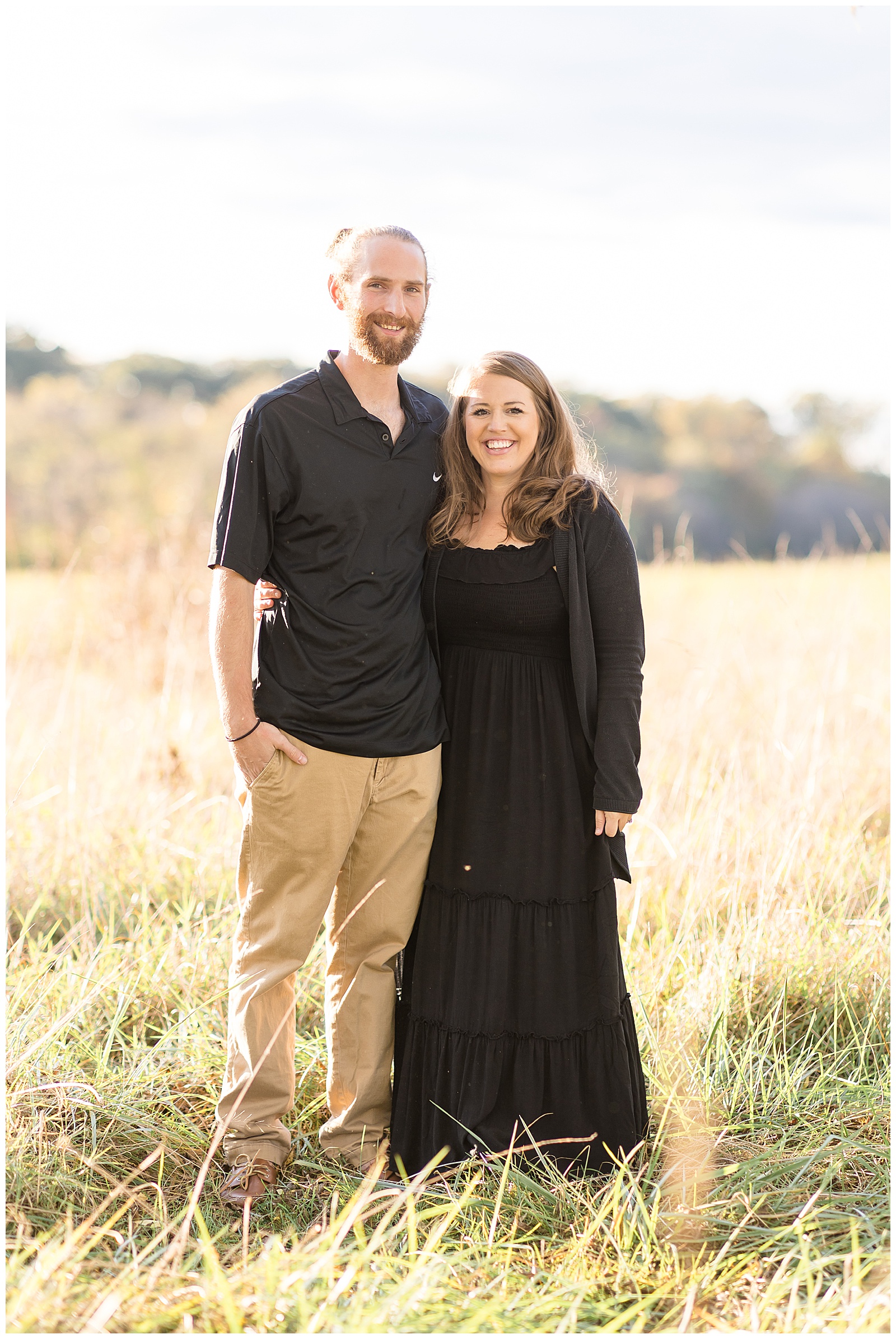 Husband and wife stand in a field in Richmond, VA wearing black outfits for Rebecca Rice's behind the lens membership class.