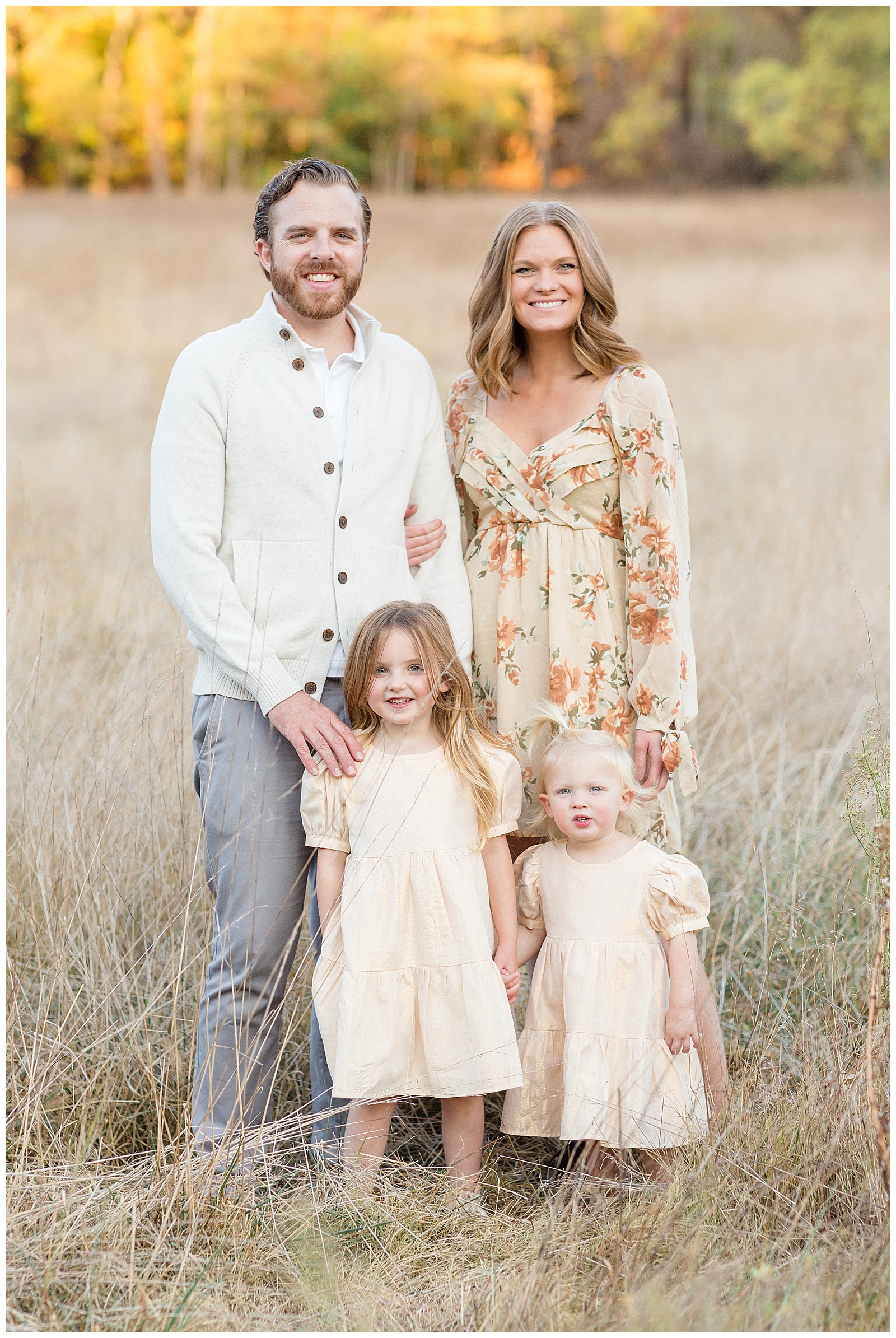 Nashville family photographer, Rebecca Rice, captures an image of a family of 4 in a Nashville field.  They wear coordinating outfits of a pale yellow, cream, and mom wears floral.