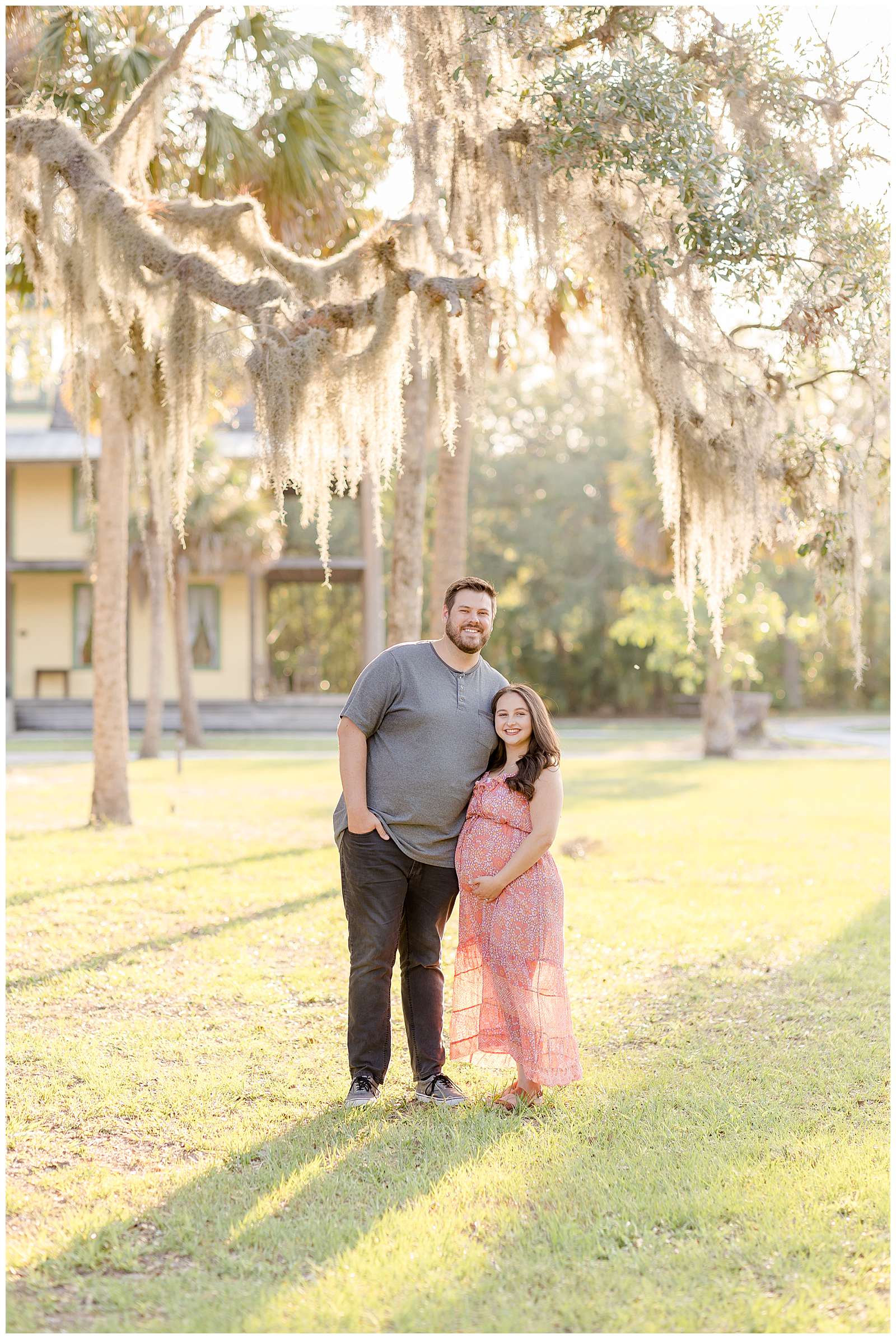 Couple with a foot and a half height difference stand in Florida, low cut grass with hanging moss trees above them as they smile at the camera with an expecting baby belly!  Click to see more of this session on the blog today!
-rebeccaricephoto.com