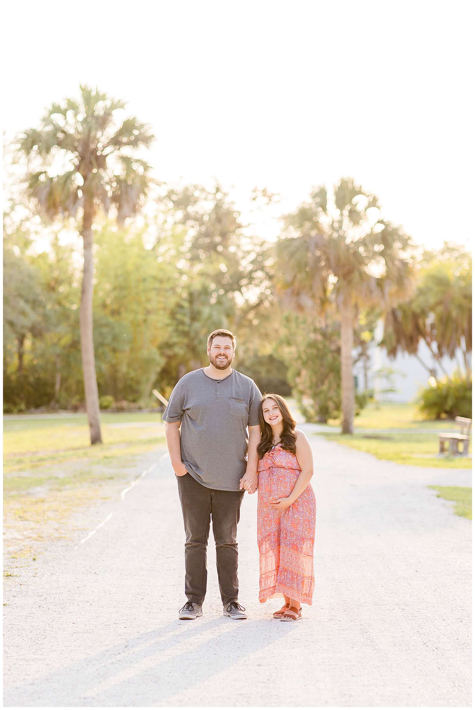 Expecting couple stands on pathway holding hands as they smile at the camera of Rebecca Rice Photography for her Behind the Lens Membership!  Click to see more of this BIG height difference couple on the blog today!
-rebeccaricephoto.com