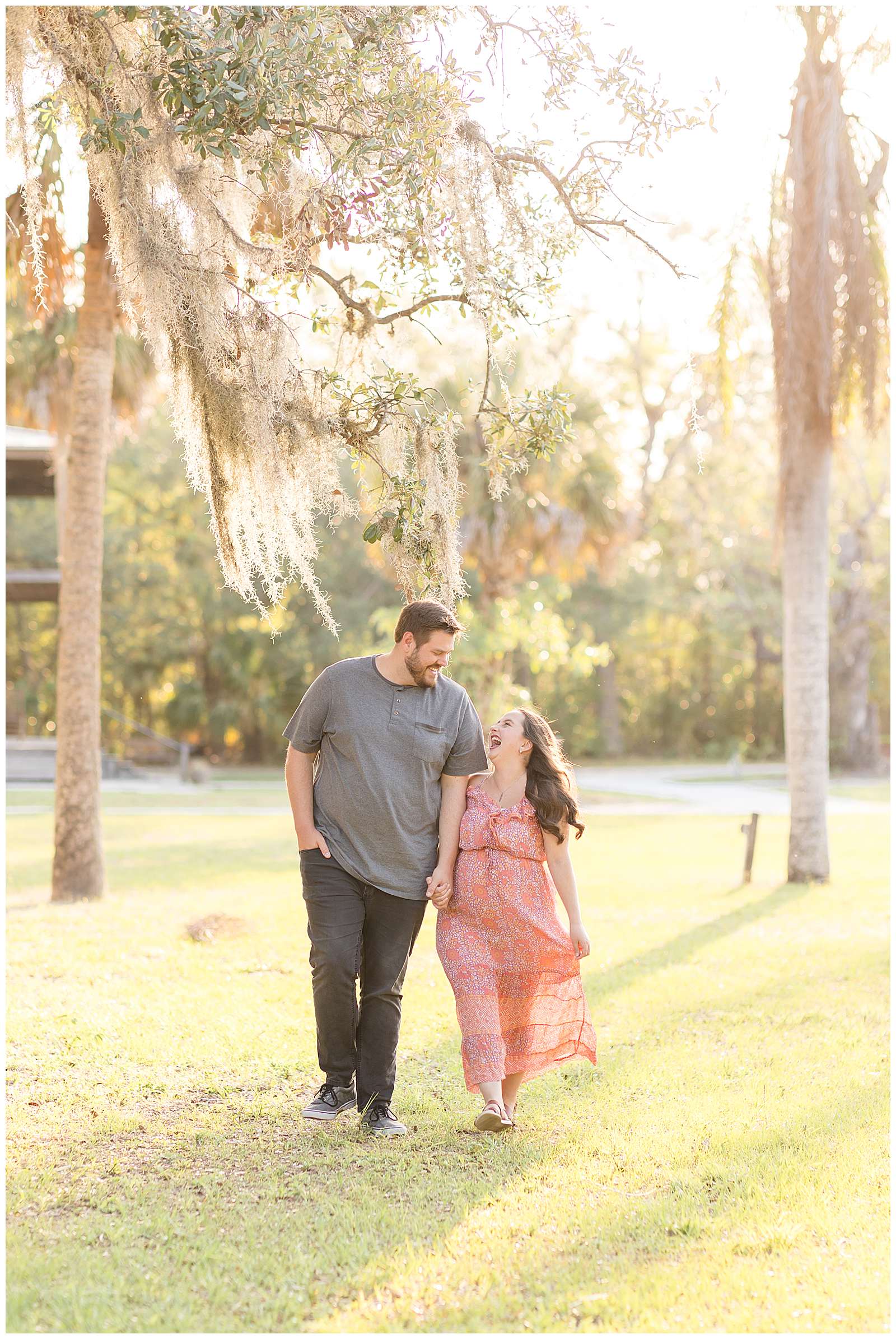 Rebecca Rice Photography capture a BIG height difference for her Behind the Lens membership community.  Couple holds hands and walks together through Florida grass and low hanging moss tress as they laugh together!
-rebeccaricephoto.com