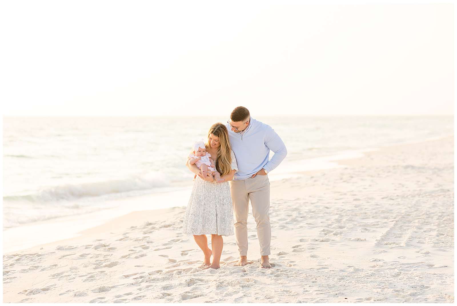 Couple stand together as wife holds her new baby girl in her arms and Dad looks down at her as they stand for their family session with Rebecca Rice Photo at Rosemary Beach!  Click to see more on the blog today! -rebeccaricephoto.com