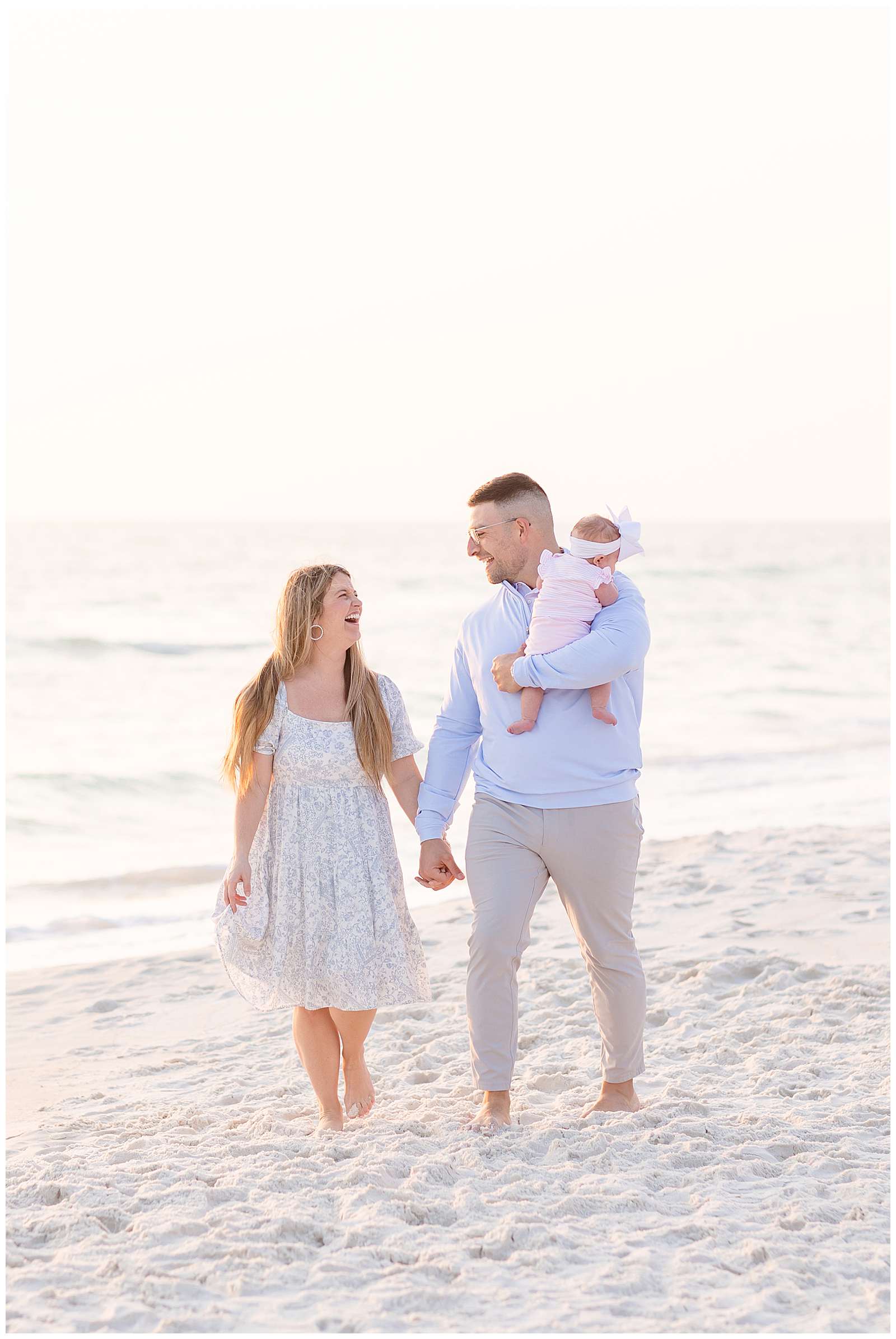 Rosemary family beach session with Rebecca Rice Photo has new parents holding hands and looking at each other as they walk along the beach and the husband holds their baby girl in one arm as she looks over his shoulder.  Click to see more of this family on the blog today!  -rebeccaricephoto.com