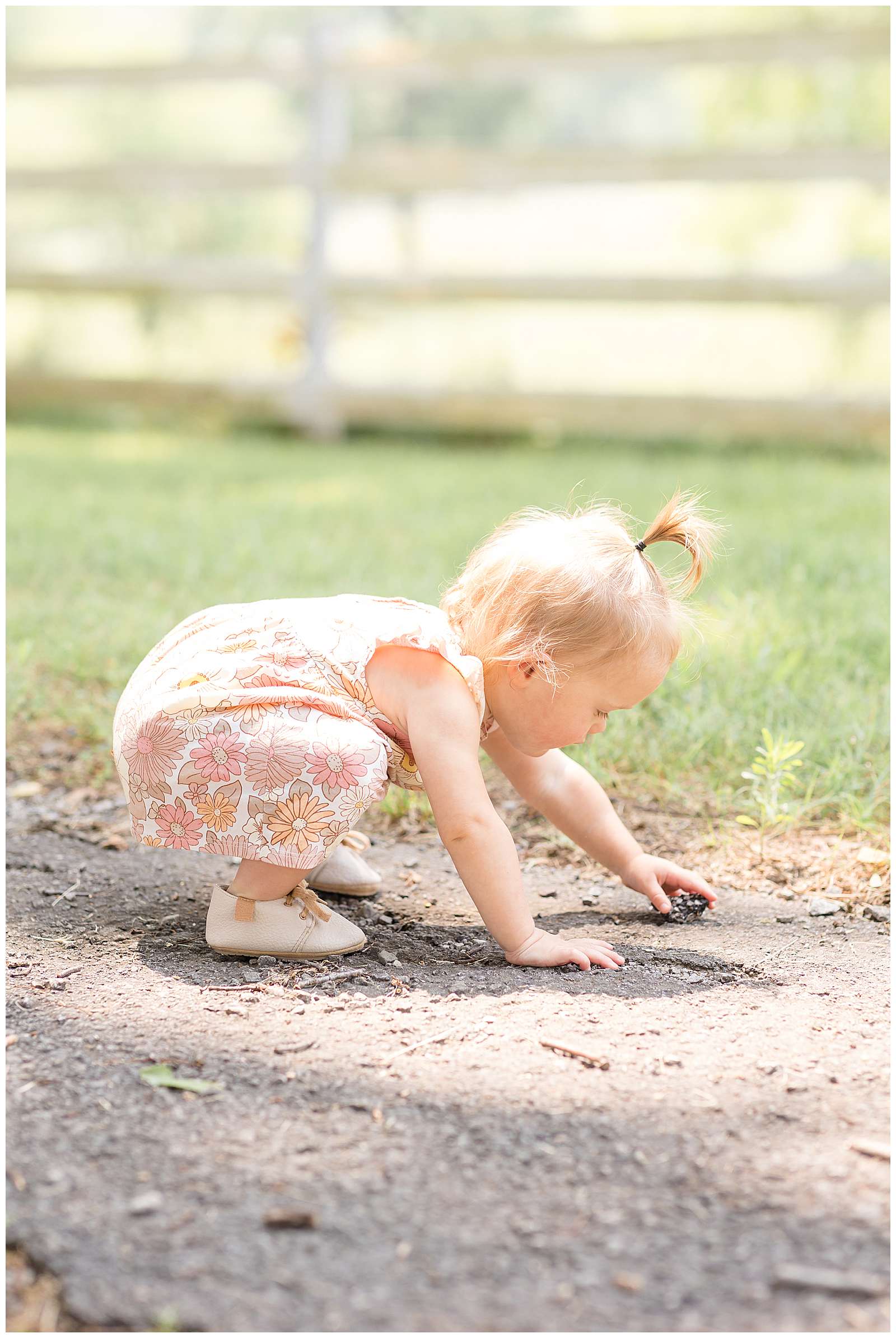 One year old girl bends down to play with the loose gravel during their Nashville family photography session. See this cute little whale, sprout ponytail girl on the blog today with her twin sister! -rebeccaricephoto.com