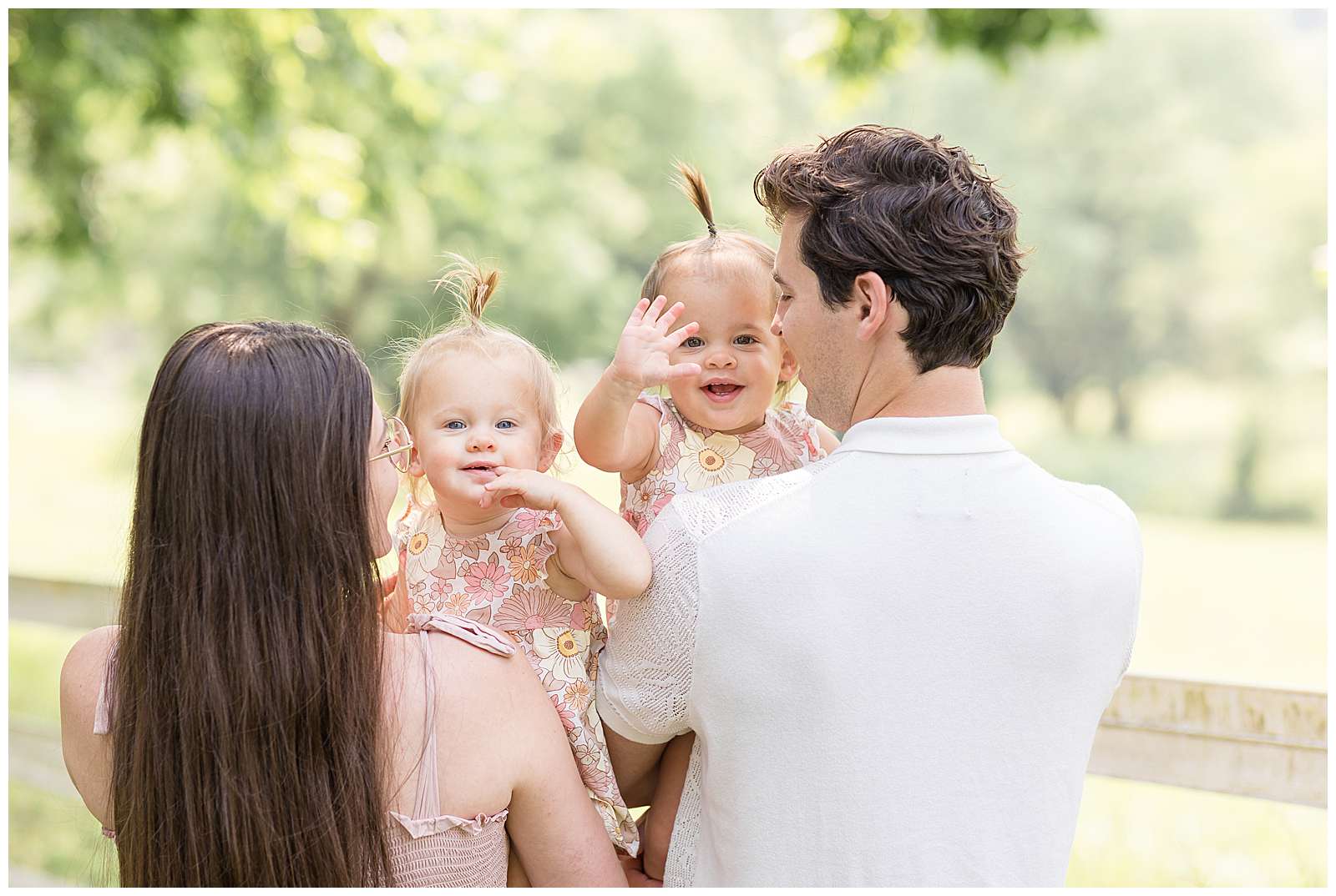 One year old twin girls look over the shoulder of their parents at Rebecca Rice who is capturing their Nashville session for her photography education membership. Click to see more of this family and watch Rebecca behind the scenes! -rebeccaricephoto.com